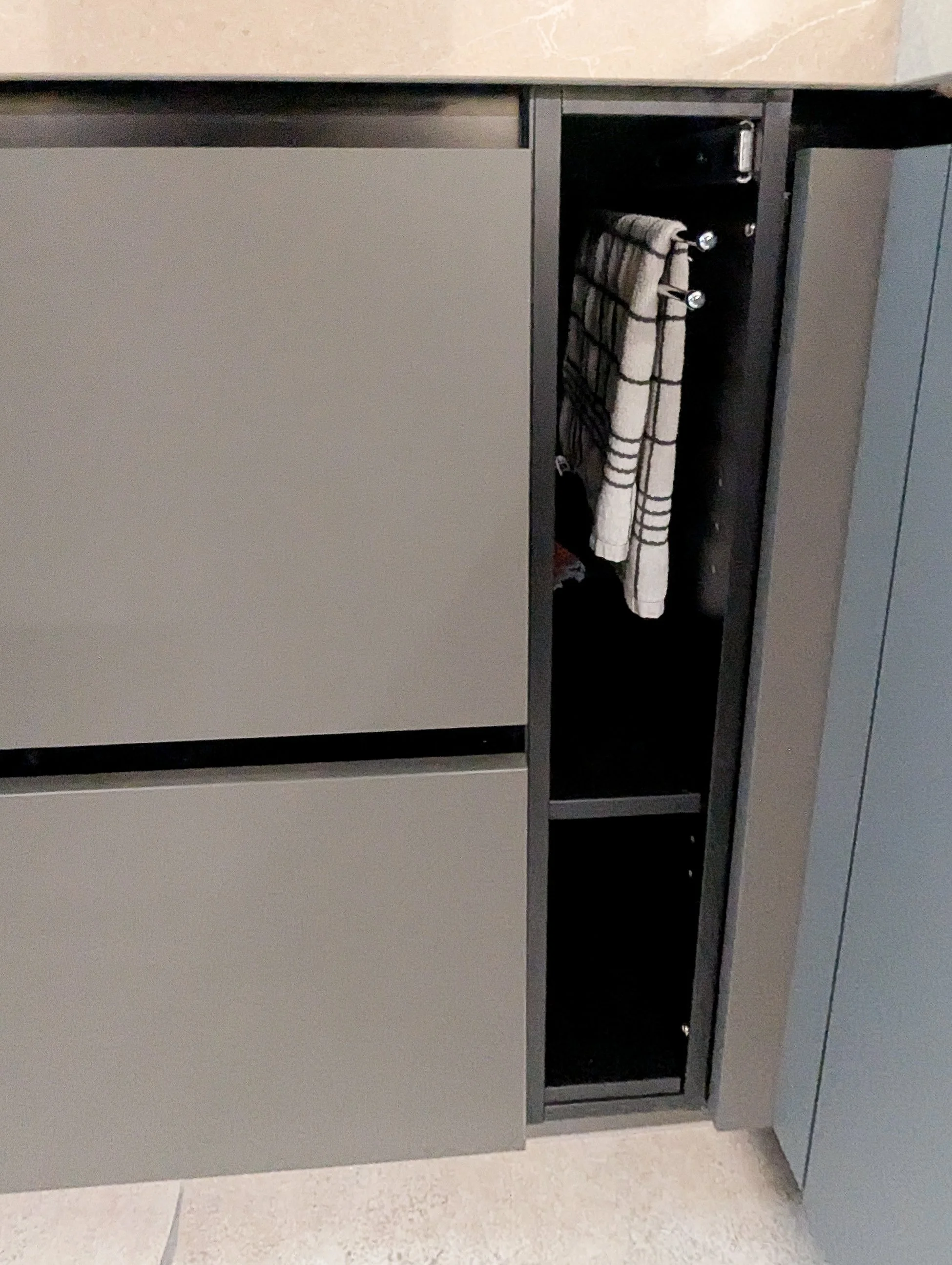 Een kast met een open vak waarin een handdoek hangt.