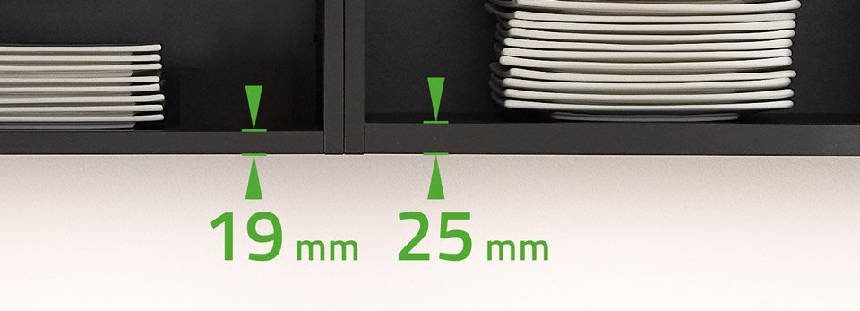 Close-up van een zwart kastje met gestapelde witte borden en meetlijnen in groen met afmetingen van 19 mm en 25 mm omhoog gericht.