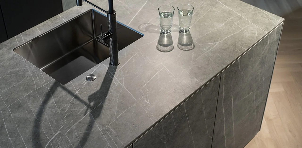 Een aanrechtblad met een ingebouwde gootsteen en twee glazen met water ernaast.