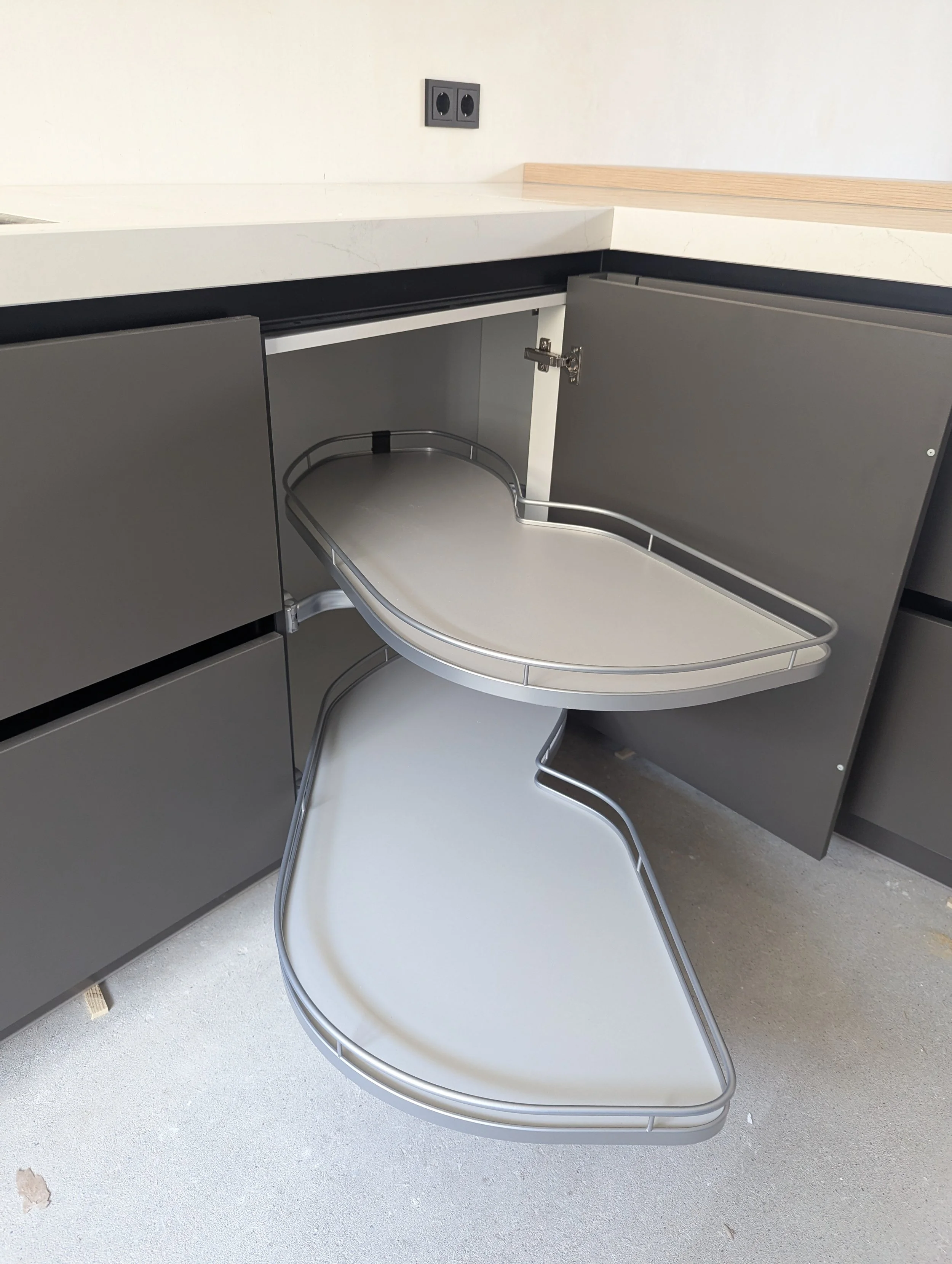 Twee uitgeklapte medische rolstoel trays in een keuken met grijze kasten en een zwarte stopcontact.