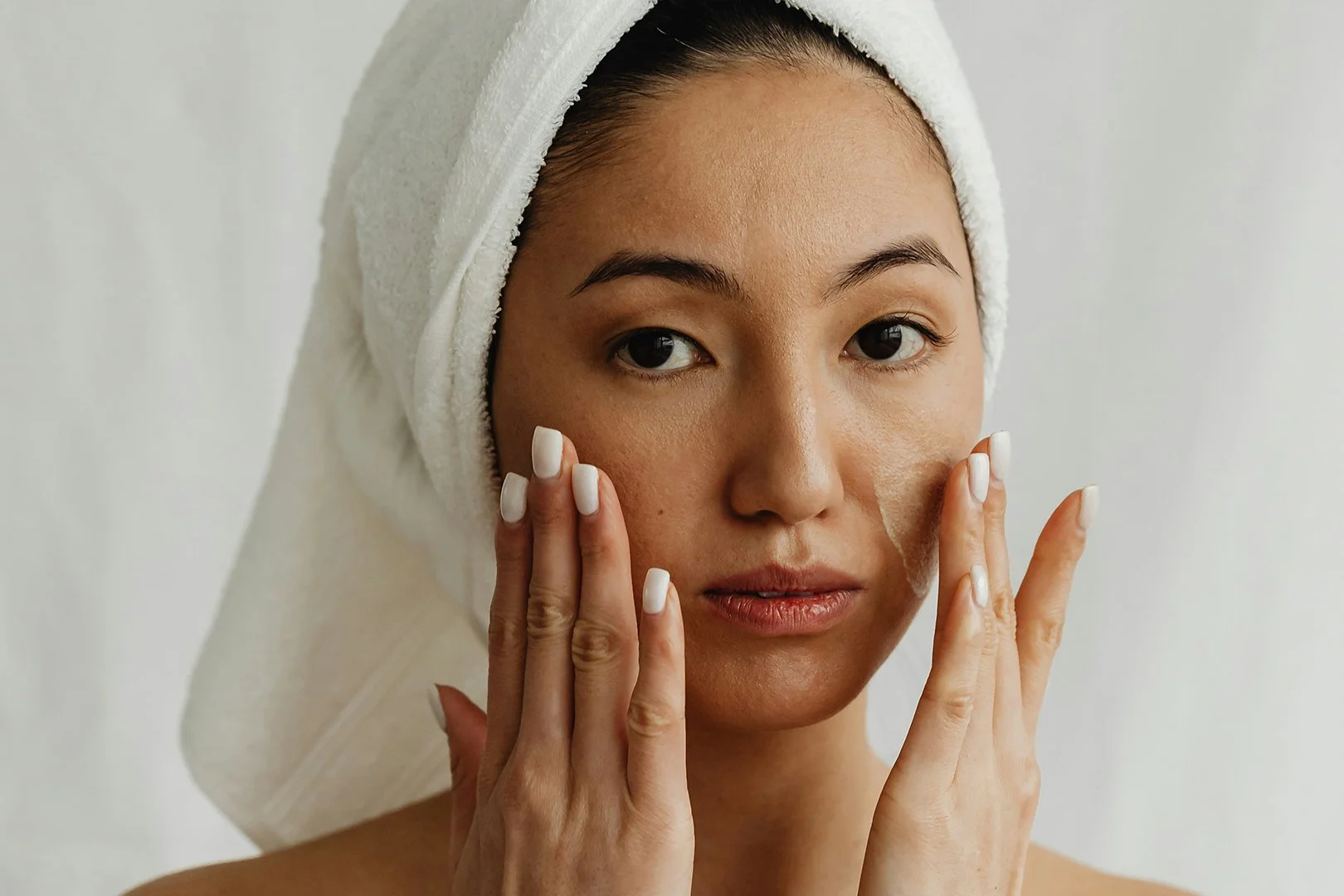 Pretty Asian woman applying face cream.