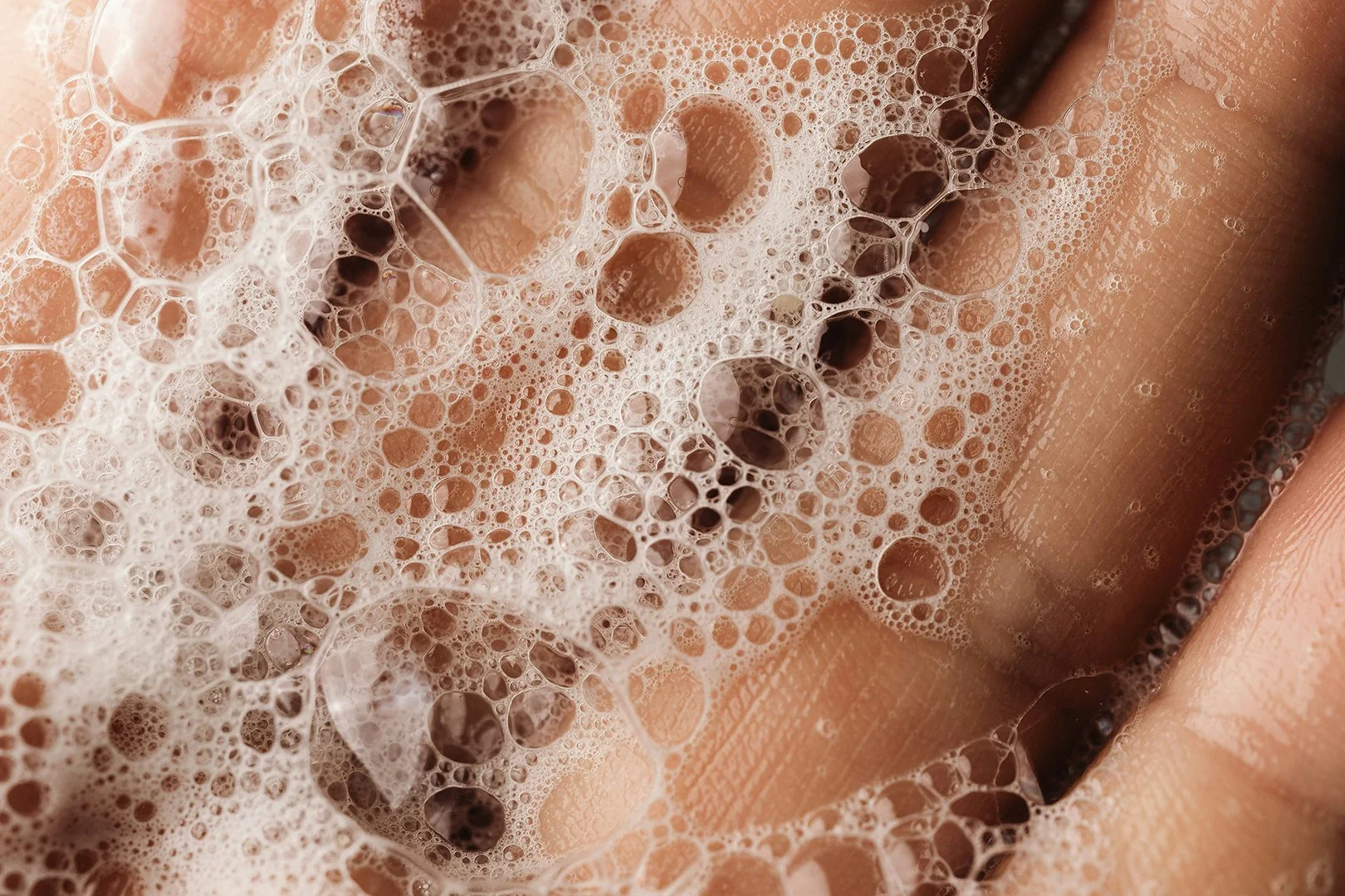 Closeup photo of human hand with bubbly soap texture.