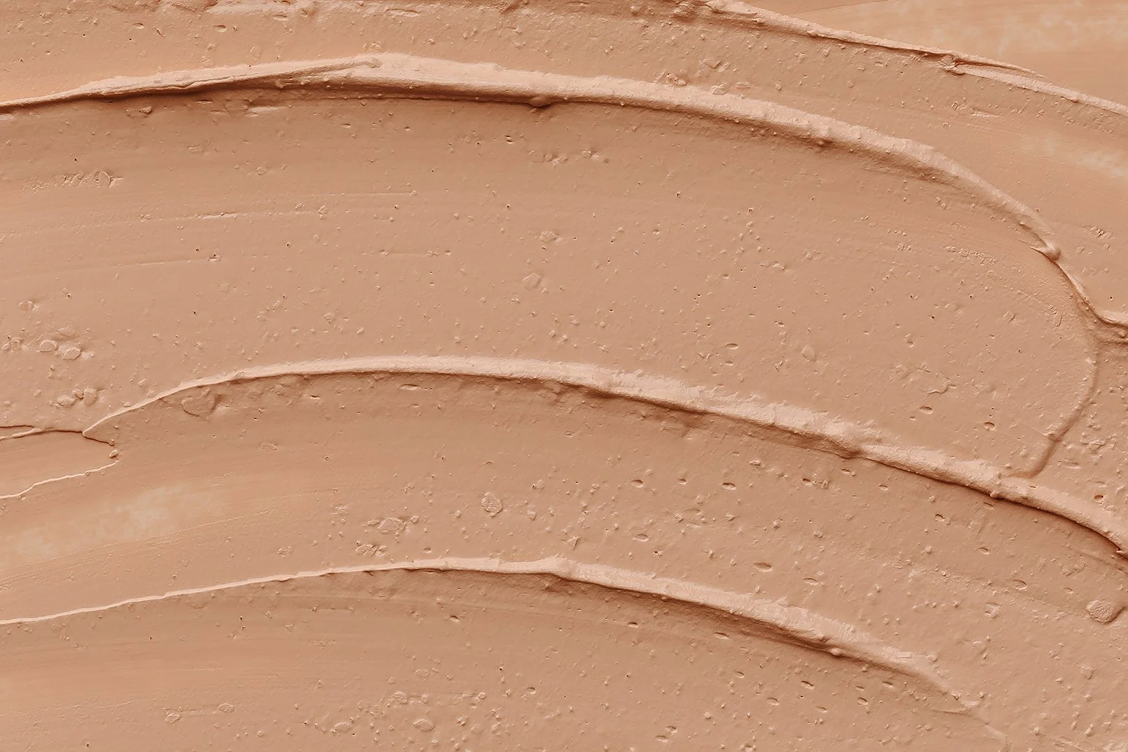 Smear of beige colored face cream or foundation on white background