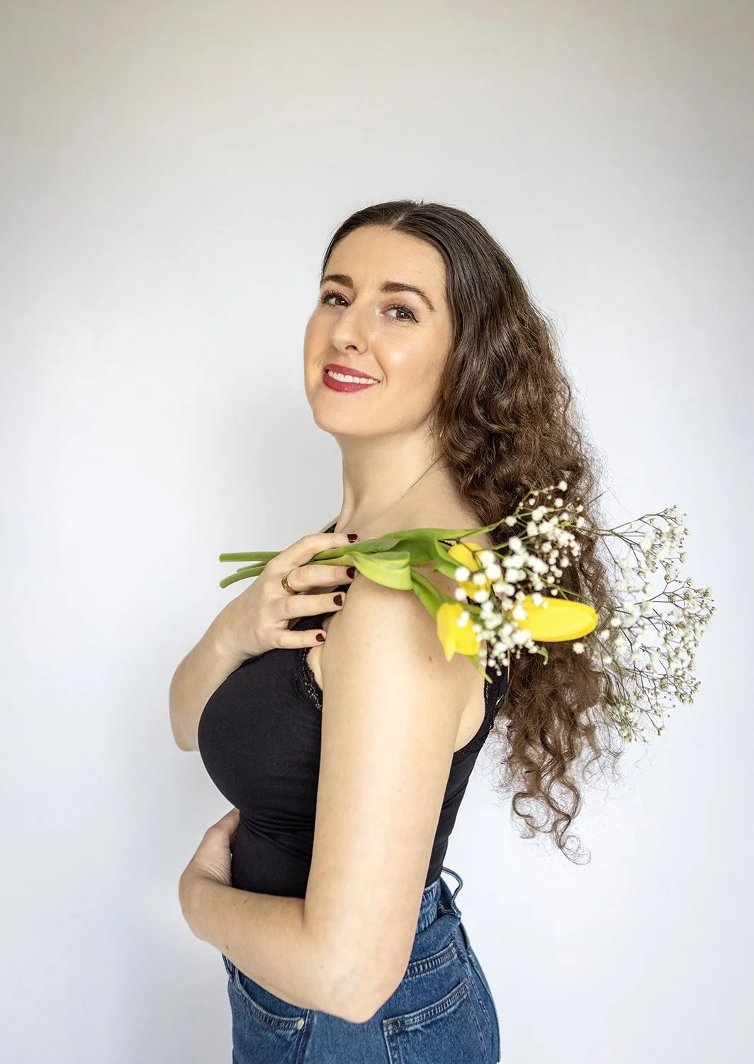 Woman holding flowers and wearing blue jeans during a professional portrait photoshoot in the Chicago suburbs.