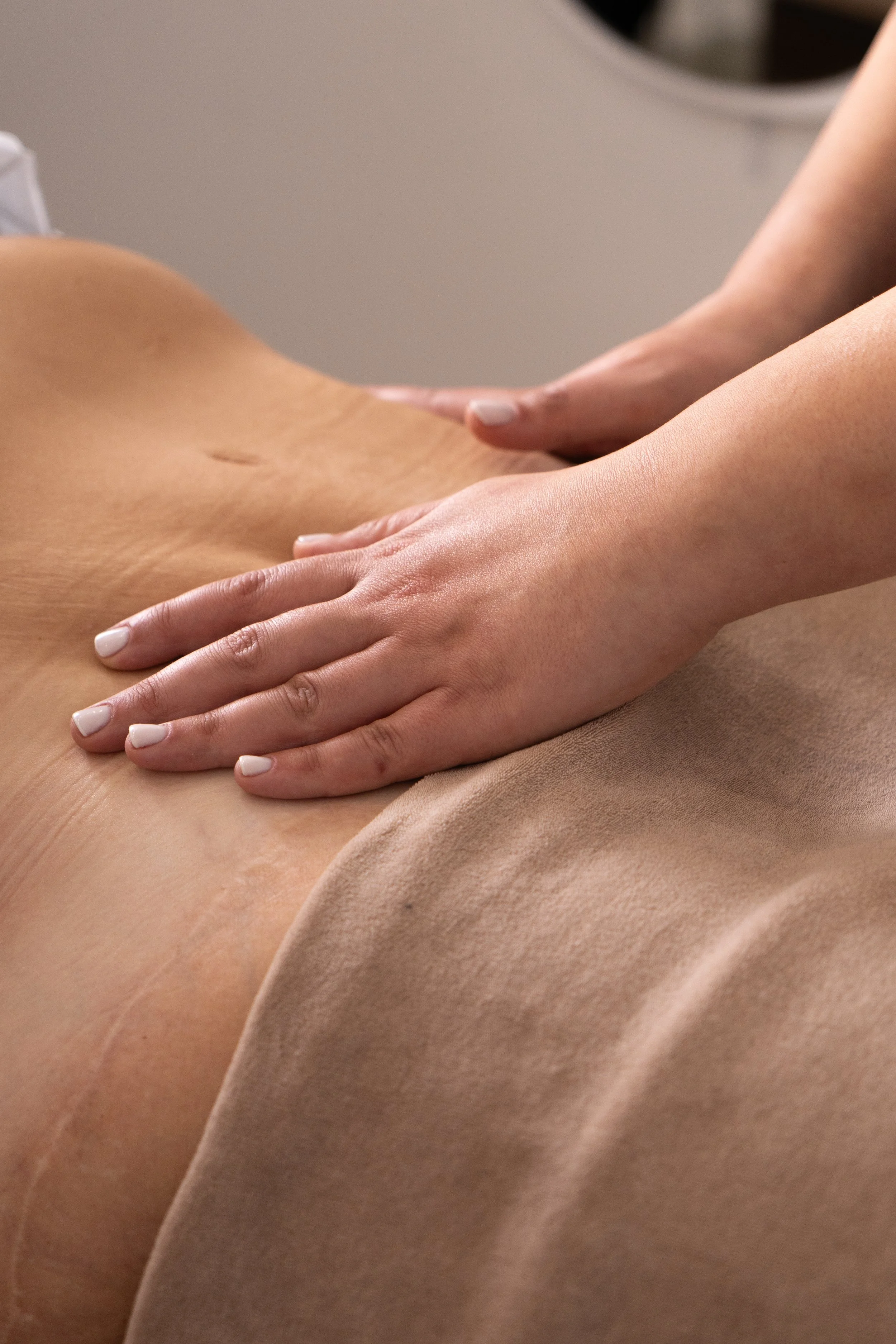 Une personne reçoit un massage sur le ventre dans un environnement de spa ou de soins du corps.
