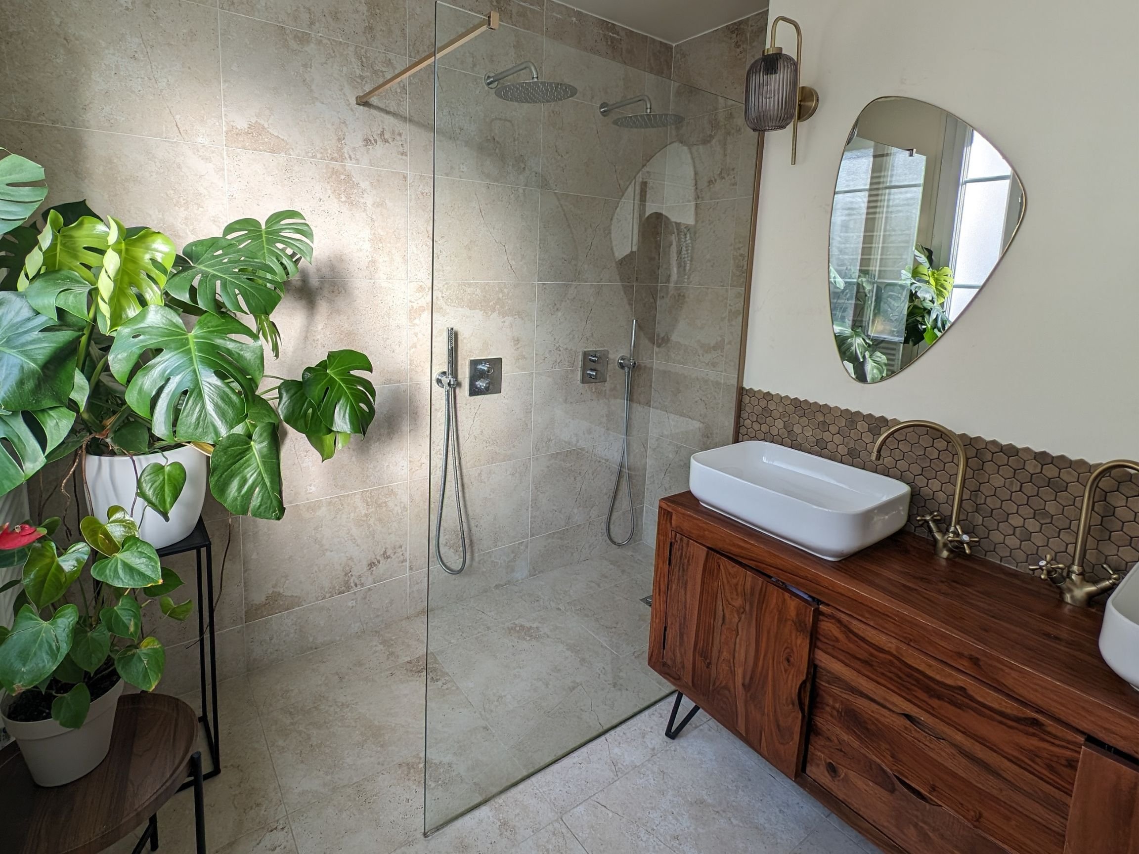 Bright and spacious relaxing bathroom with travertine stone floors, limewash walls, and a vintage sideboard repurposed as a vanity.