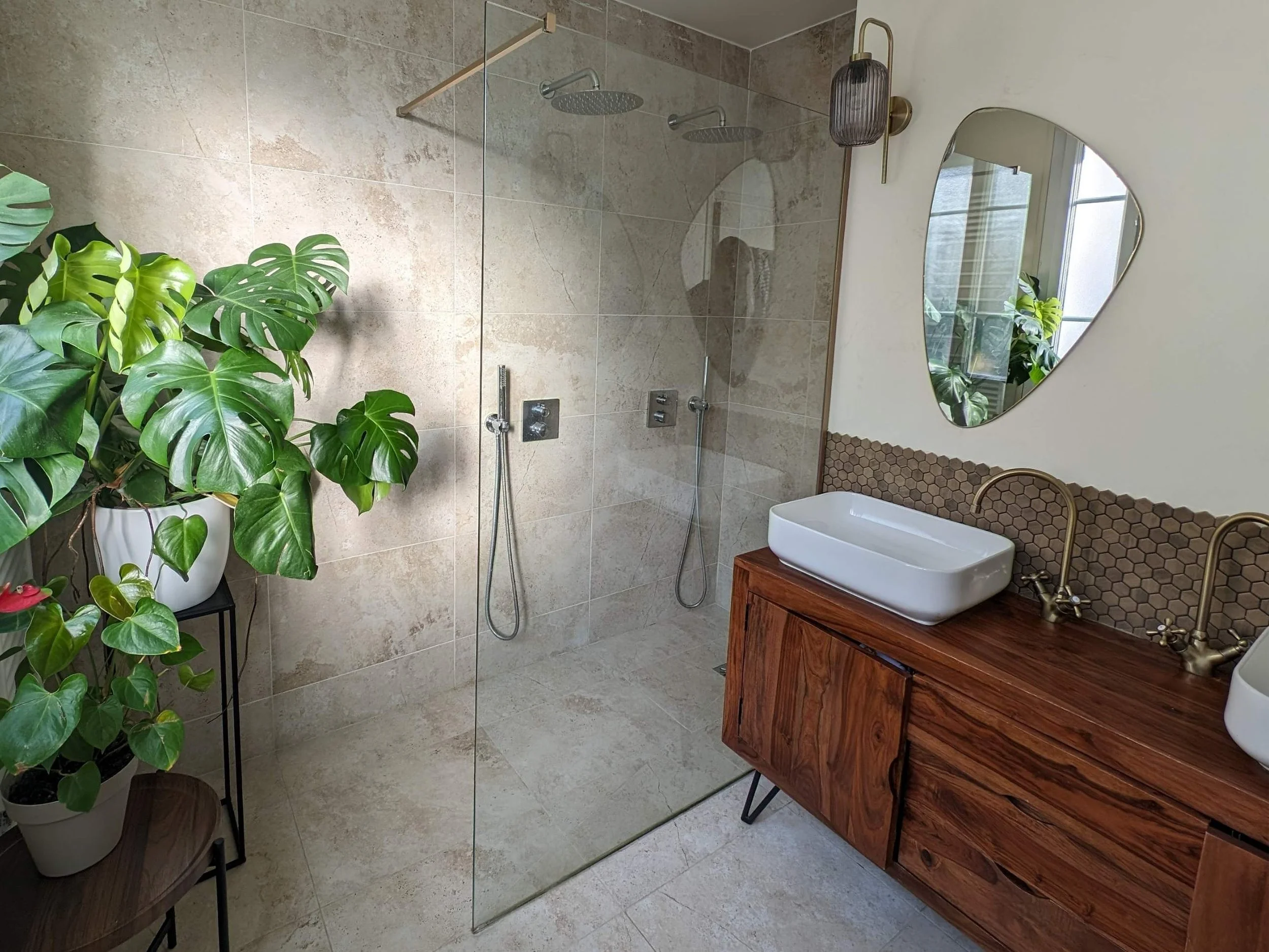 Bright and spacious relaxing bathroom with travertine stone floors, limewash walls, and a vintage sideboard repurposed as a vanity.