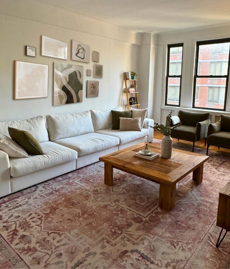 NYC Upper West Side living room featuring a white linen sofa, a coral vintage rug, a reclaimed wood coffee table, and olive green velvet accent chairs and a gallery wall. Designed with the Virtual Design Package from L'Atelier By ATB.