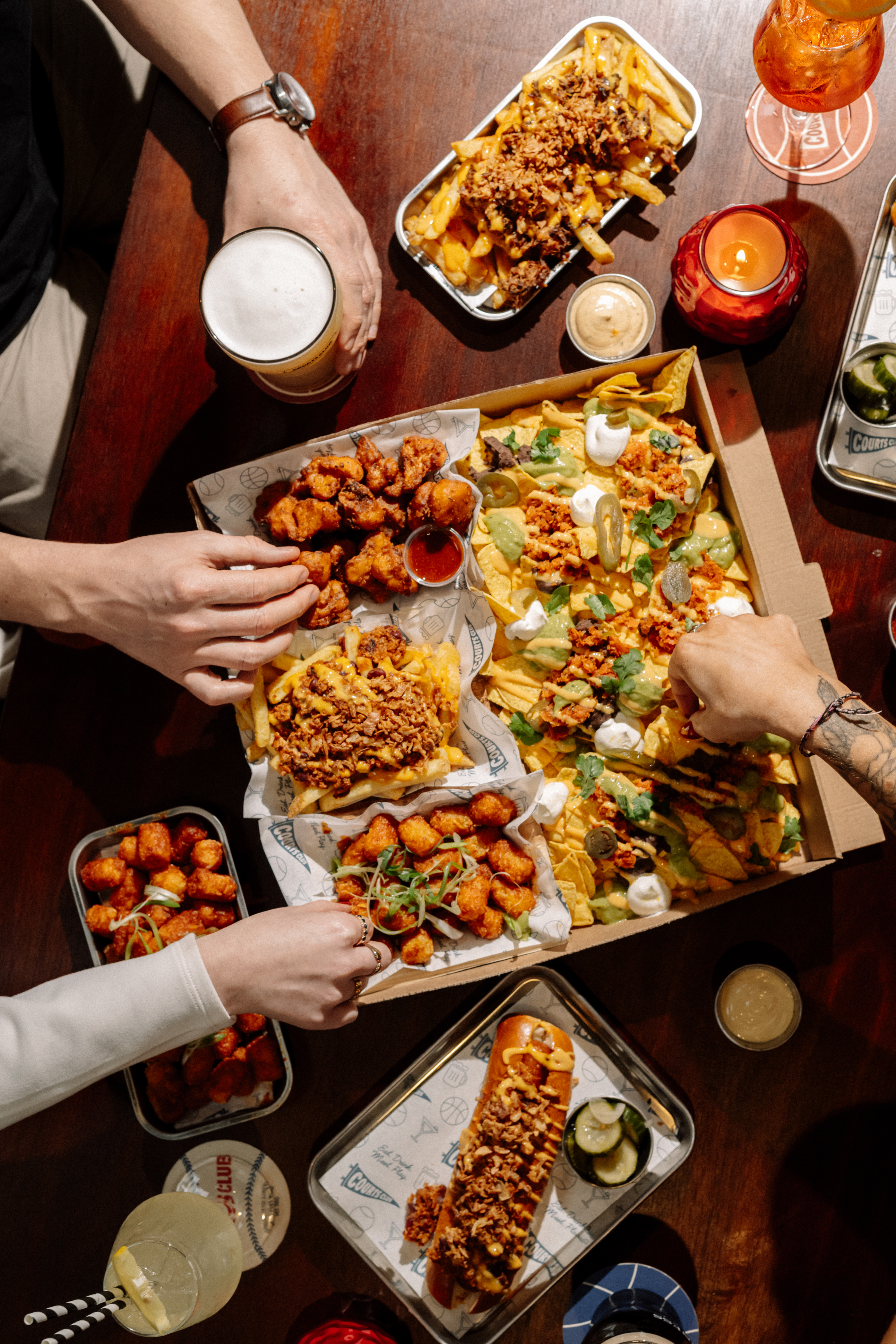 Overhead view of sharing plates, pizza and drinks at Courts Club Manchester
