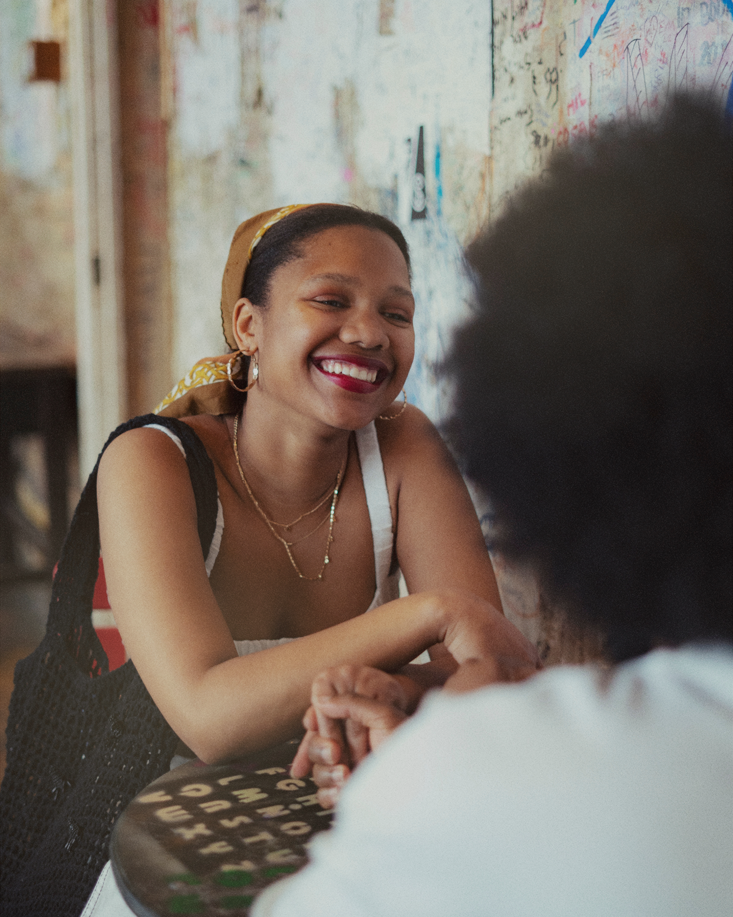 Smiling black young woman holding hands with person across from her at table