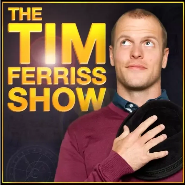 Promotional poster for The Tim Ferriss Show featuring a man with short light hair, wearing a maroon sweater and holding a black hat against a dark background.