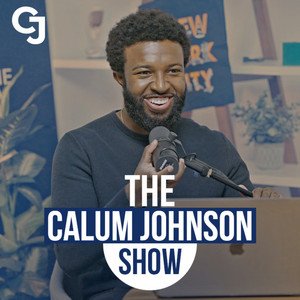 A man with a beard and curly hair speaking into a microphone at a show titled 'The Calum Johnson Show', with a background that includes books and a poster.
