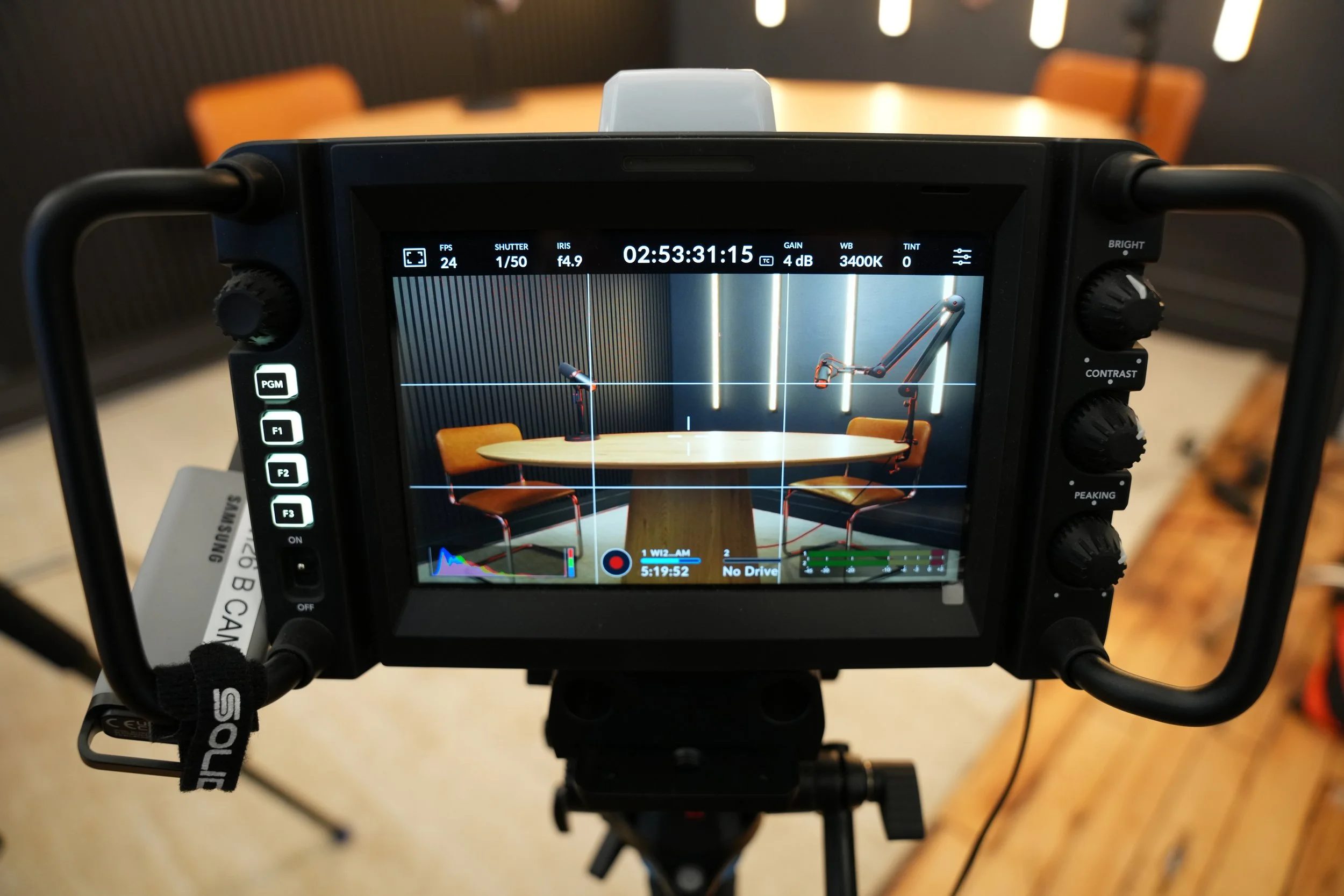 Video camera monitor displaying a conference room setup with microphones, a table, and chairs.