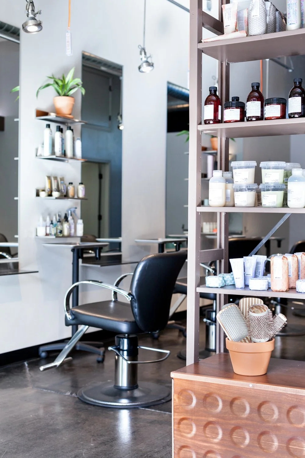 Modern hair salon interior with styling chair, shelves with hair products, and hairbrushes in a pot.