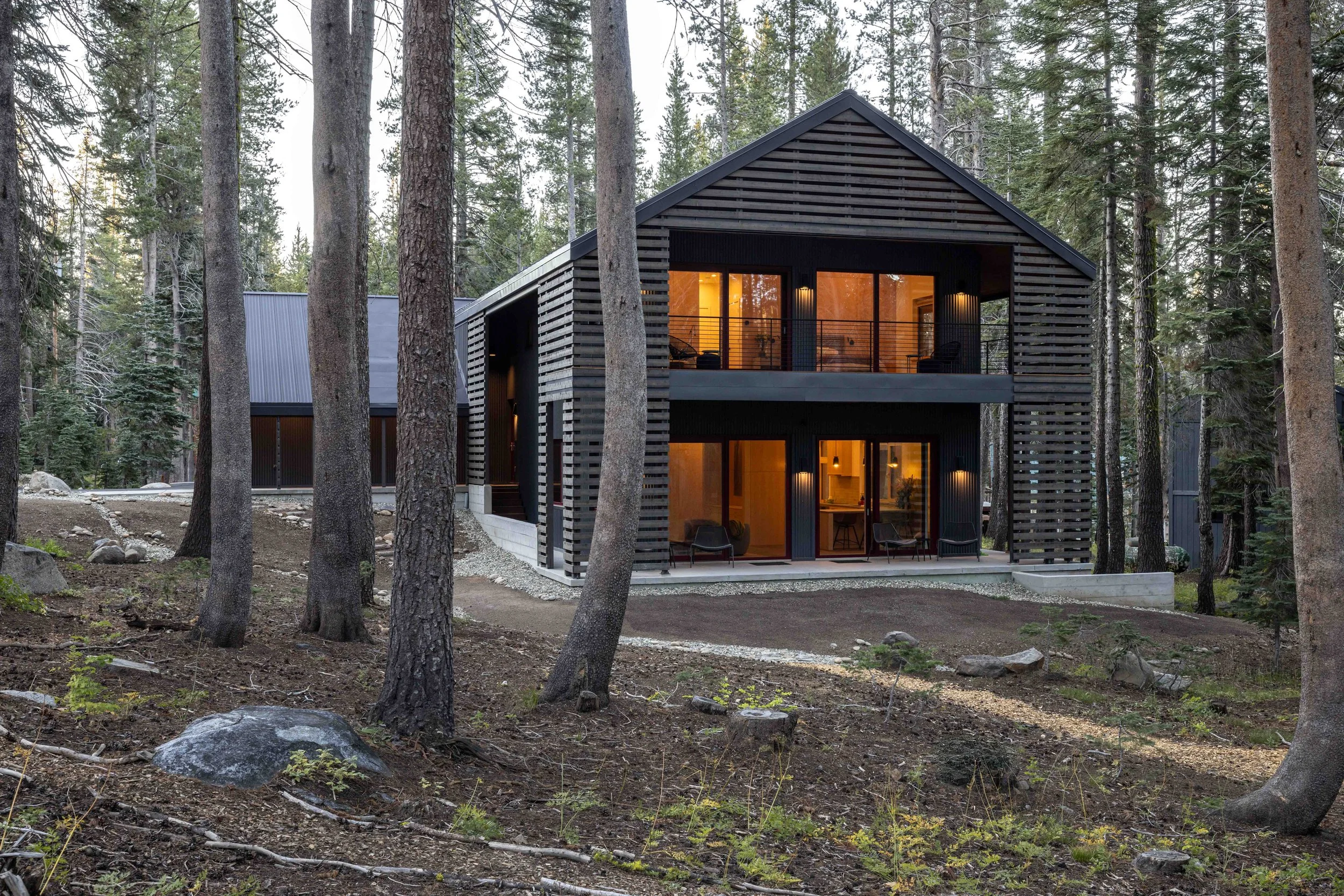 High performance zero net energy home at dusk with warm interior lighting, designed and built by Atmosphere Design Build, Sierra Nevada foothills