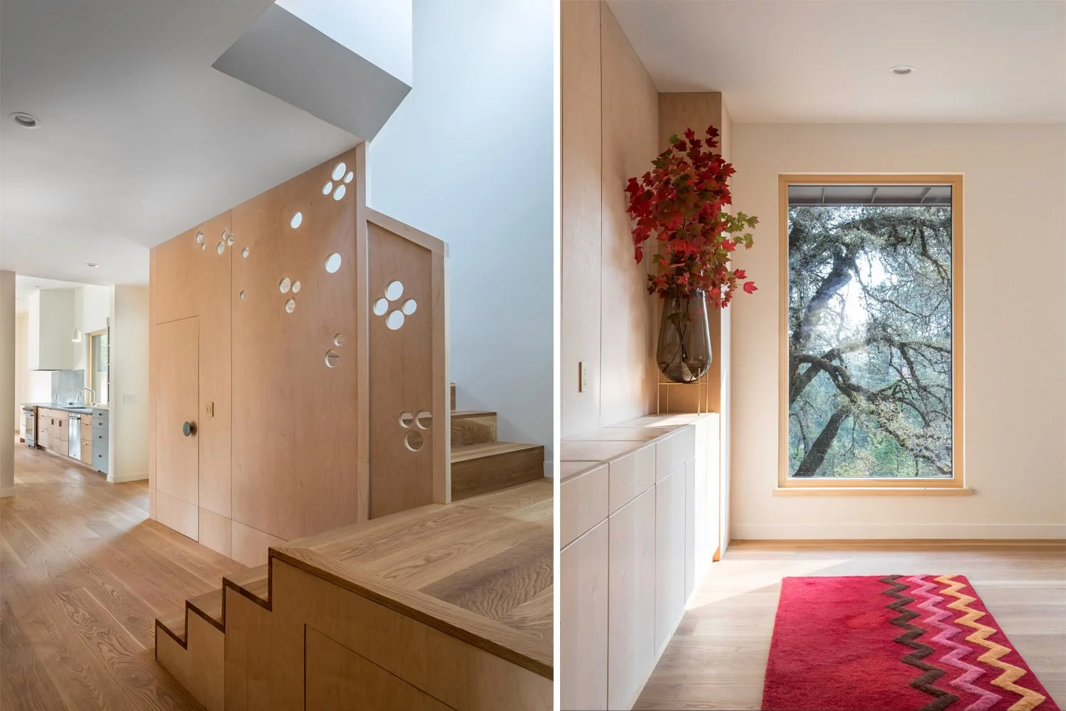 Modern interior with light wood staircase and cabinets, circular cut-out designs, a large window, decorative vase with branches, and a colorful zigzag rug.