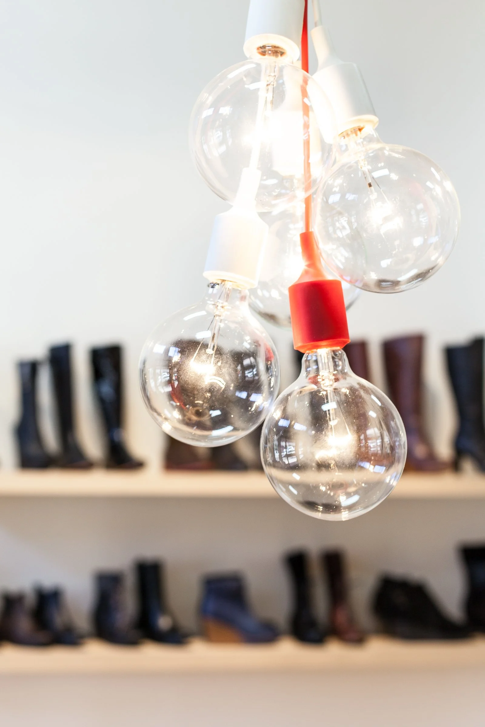 Close-up of hanging light bulbs with shelves of boots in the background.