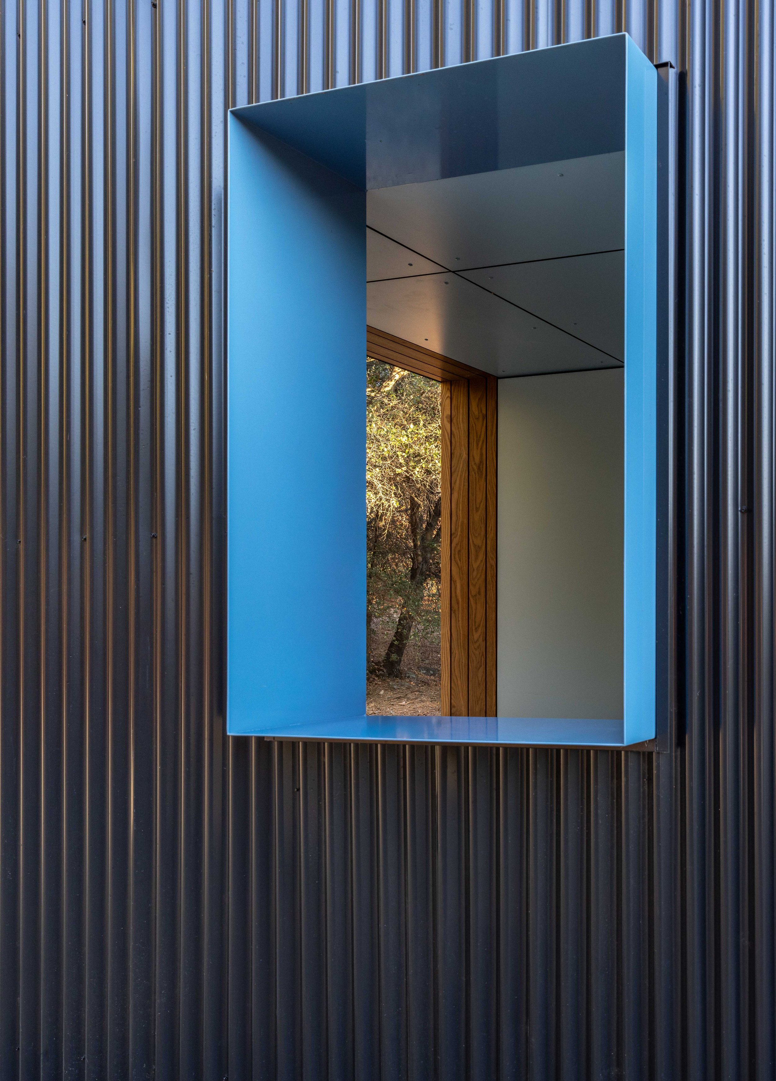 Blue window frame on corrugated metal wall with view outside