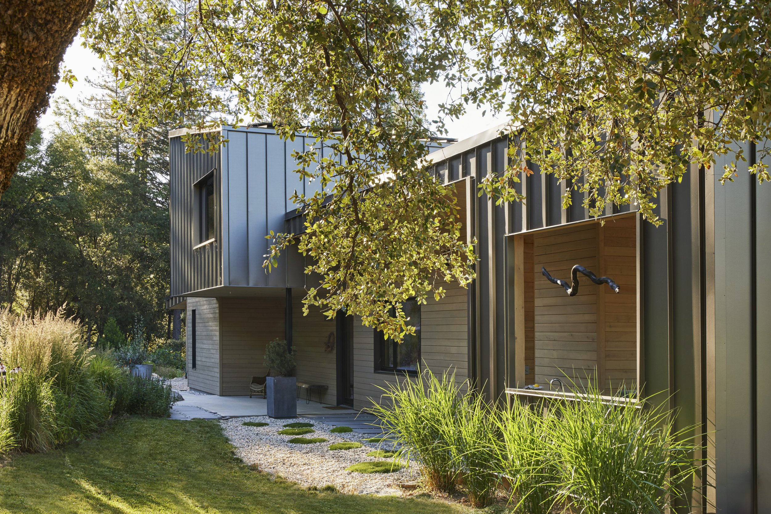 Modern house with metal and wood exterior surrounded by trees and greenery
