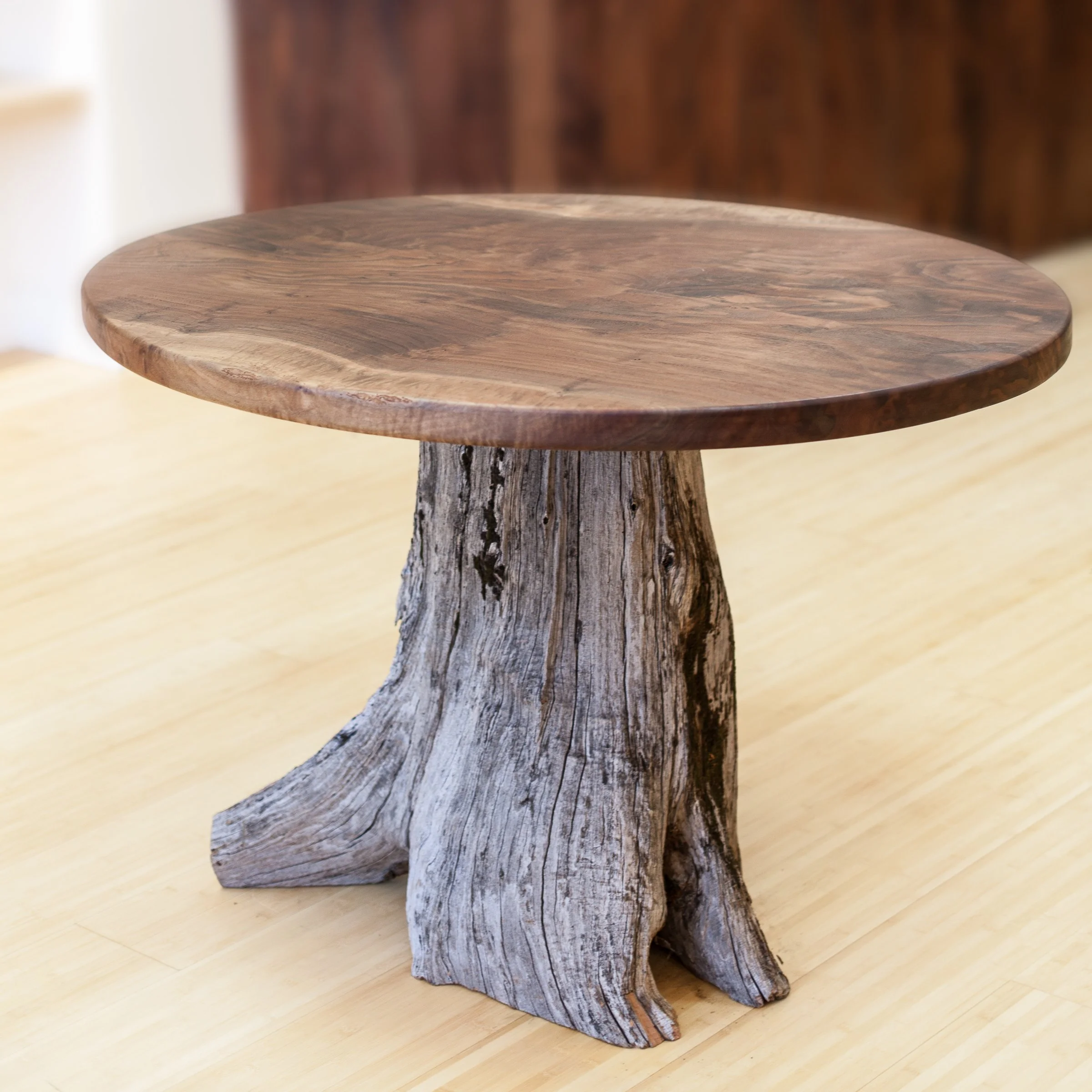 Round wooden table with driftwood base on wooden floor