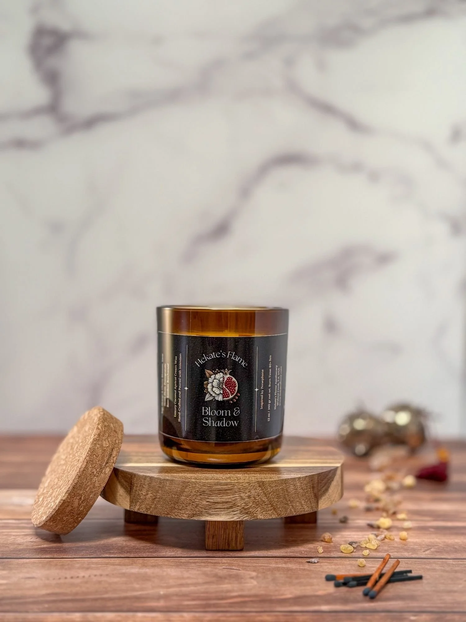 Small amber glass Bloom & Shadow candle with gold metal lid, handcrafted Greek mythology candle with coconut apricot wax.