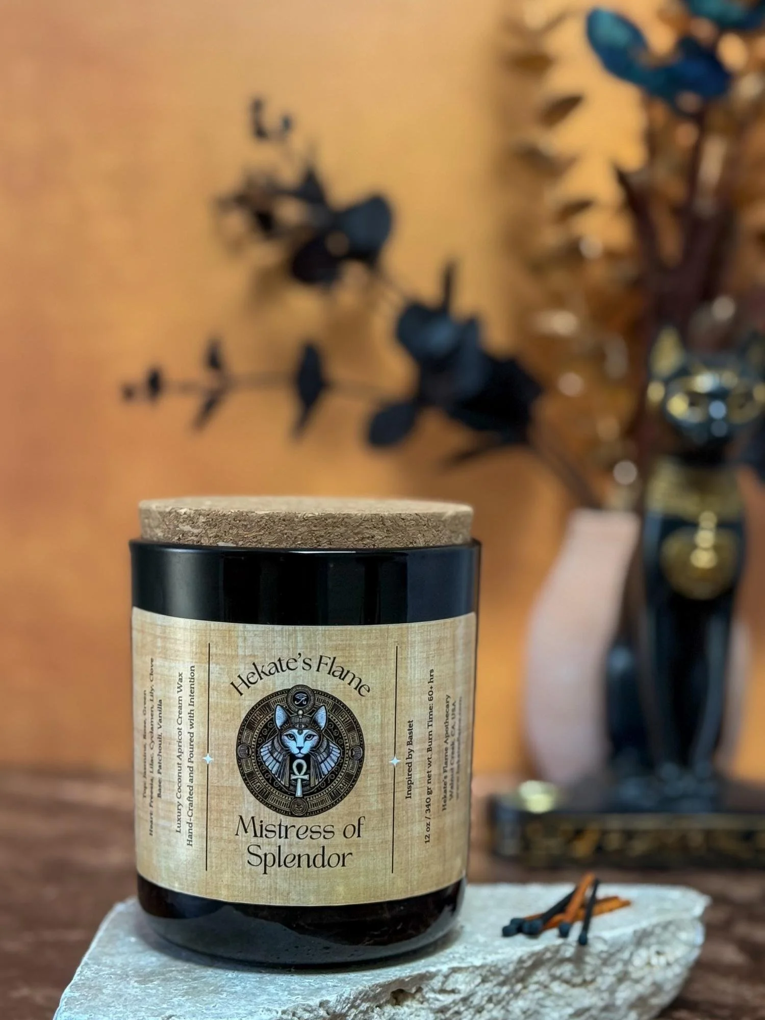 Homemade Bastet candle in dark glass jar with cork lid, mythology-inspired Mistress of Splendor design.