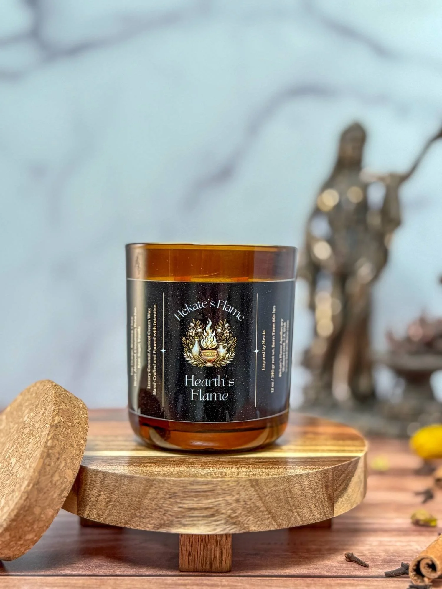 Luxury Greek mythology candle in amber glass jar with cork lid, hand-poured coconut apricot wax and eco-conscious wooden wick.