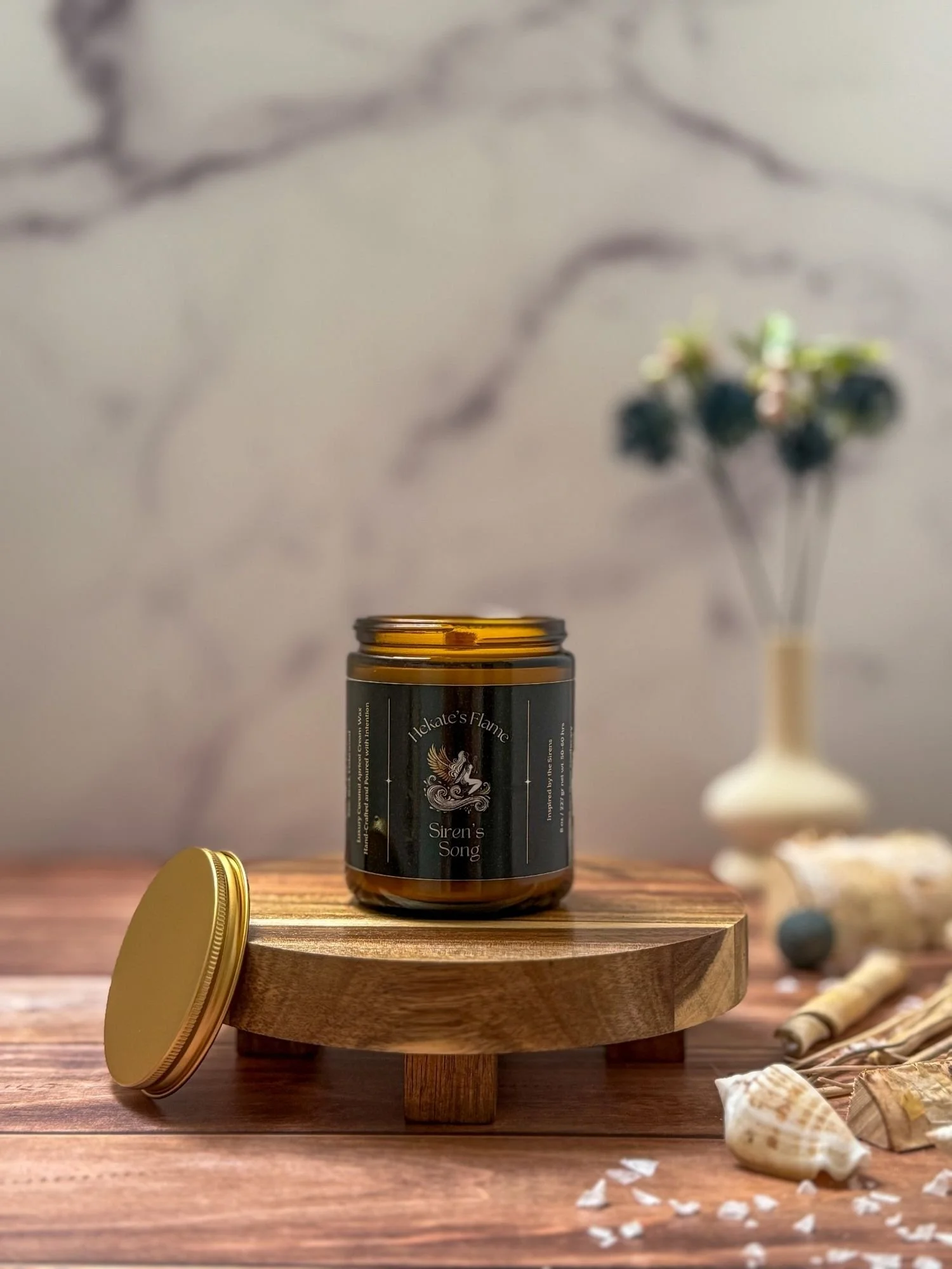 Amber glass Siren’s Song mythology candle shown open with gold lid, luxury eco-conscious coconut apricot wax.