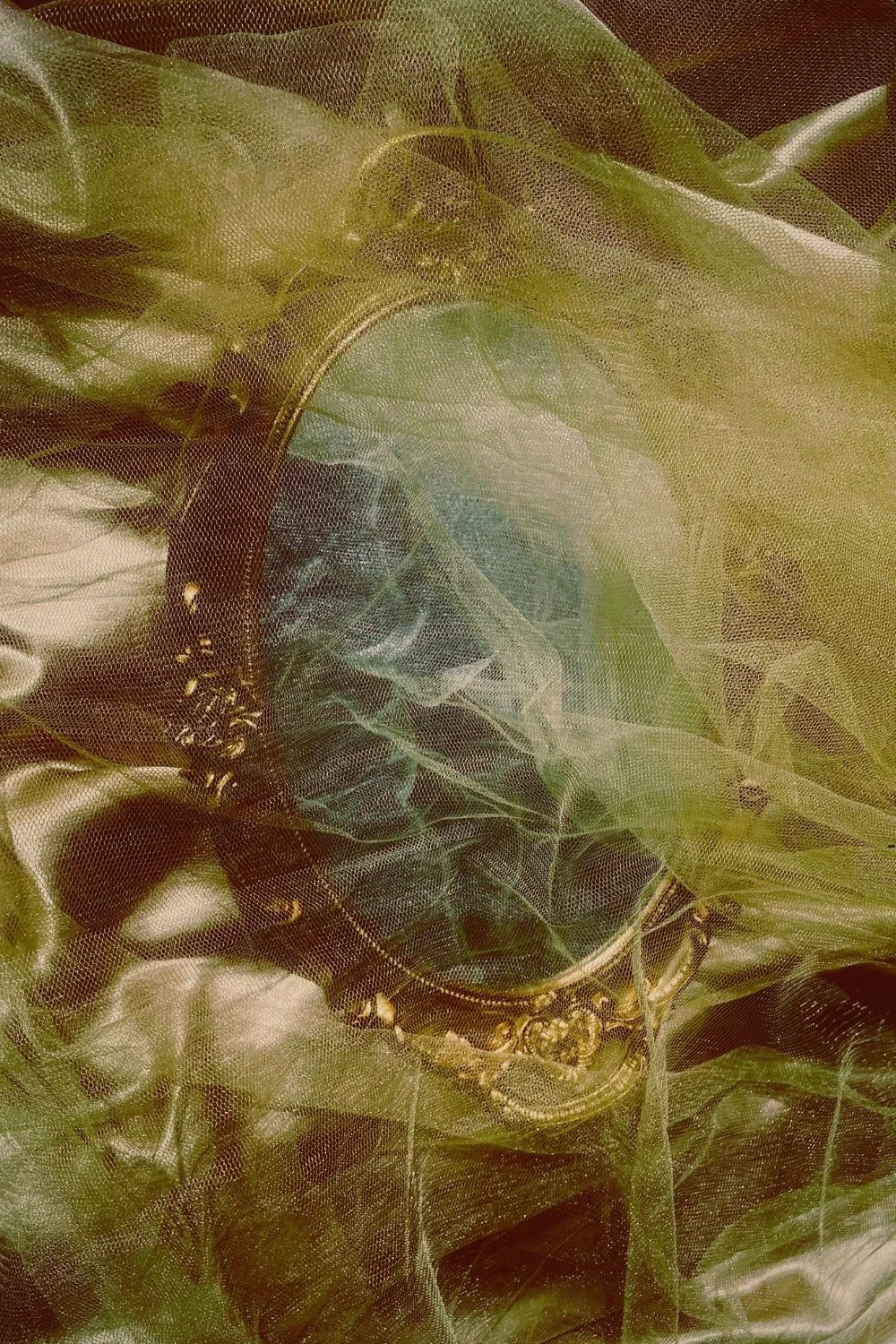 Antique mirror veiled in green cloth referencing Medusa’s myth for handmade mythology candles with clean-burning wooden wicks.