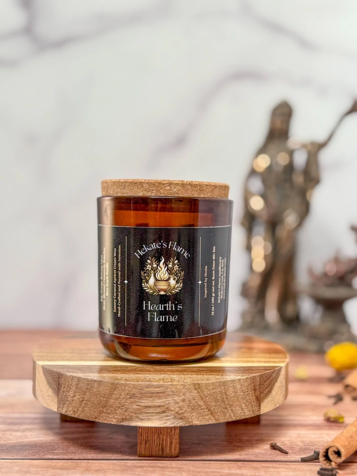 Eco-conscious myth-inspired candle, Hearth’s Flame, in amber jar with cork lid, hand-poured coconut apricot wax and wooden wick.