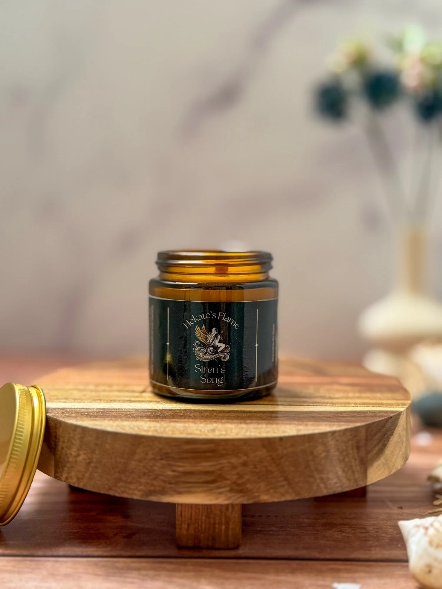 Handcrafted Siren’s Song candle in amber glass jar, gold lid removed, luxury eco-conscious wooden wick mythology candle.