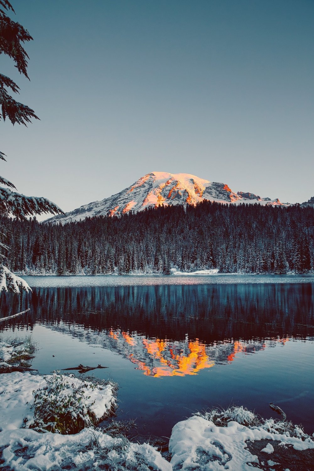 Frosted evergreens around a glacial lake at sunrise, capturing Skadi’s icy wilderness for a handmade scented candle with a clean-burning wooden wick.