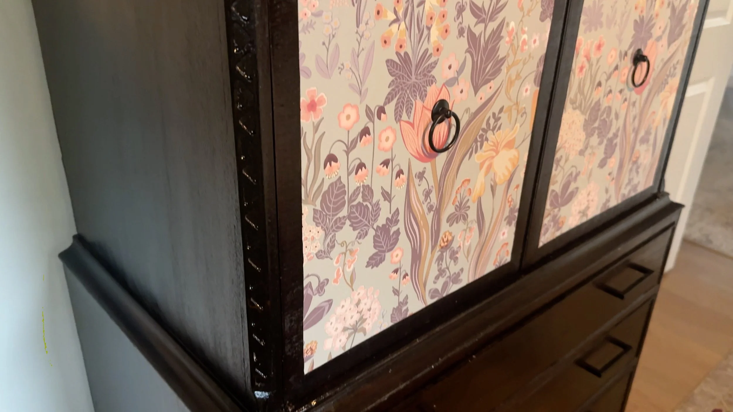 restored dark wood dresser with floral wallpaper panels and original ring pulls