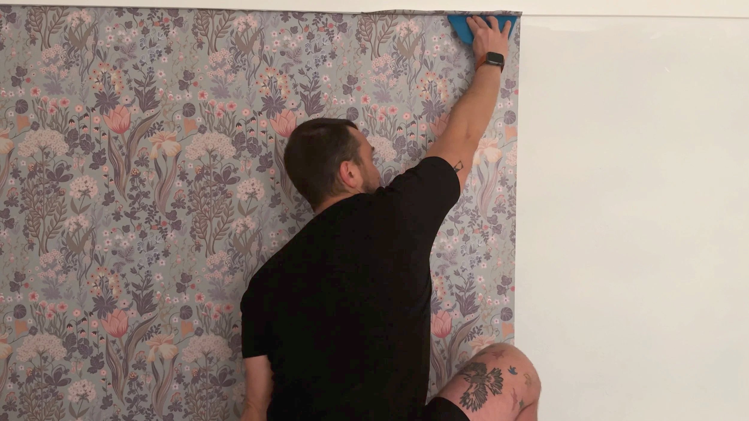 installing botanical wallpaper on a guestroom wall