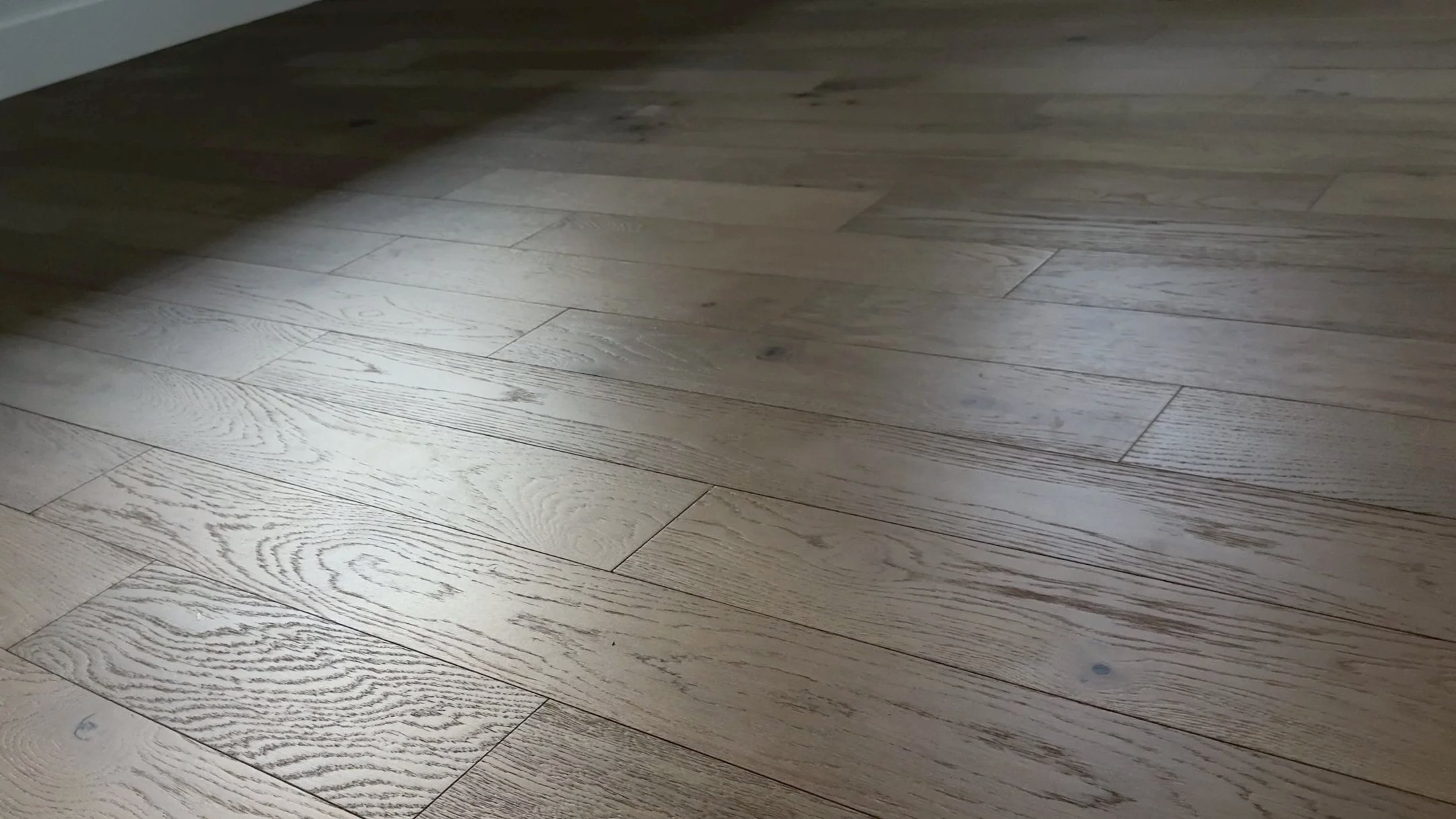 empty guest room with sunlight falling across the wood floor