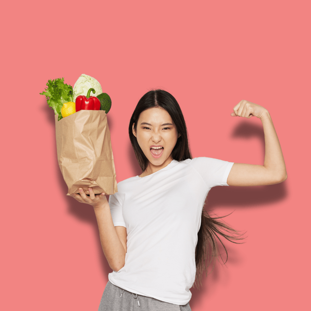 oung woman in a white shirt flexes her arm confidently while holding a paper bag of vegetables. The pink background adds vibrancy and energy.