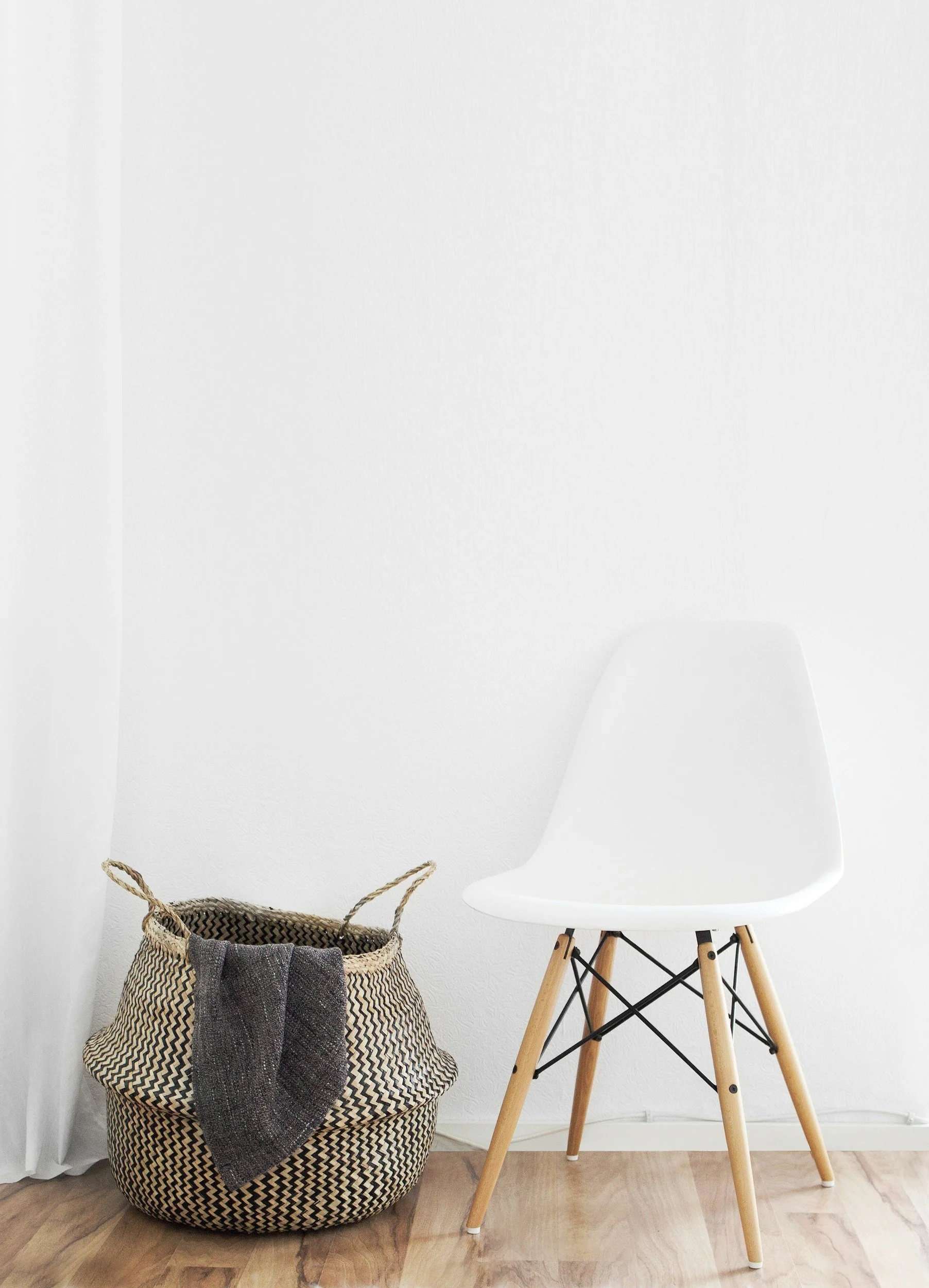 Woven storage basket with blanket beside a white chair, eco-friendly and sustainable home organization