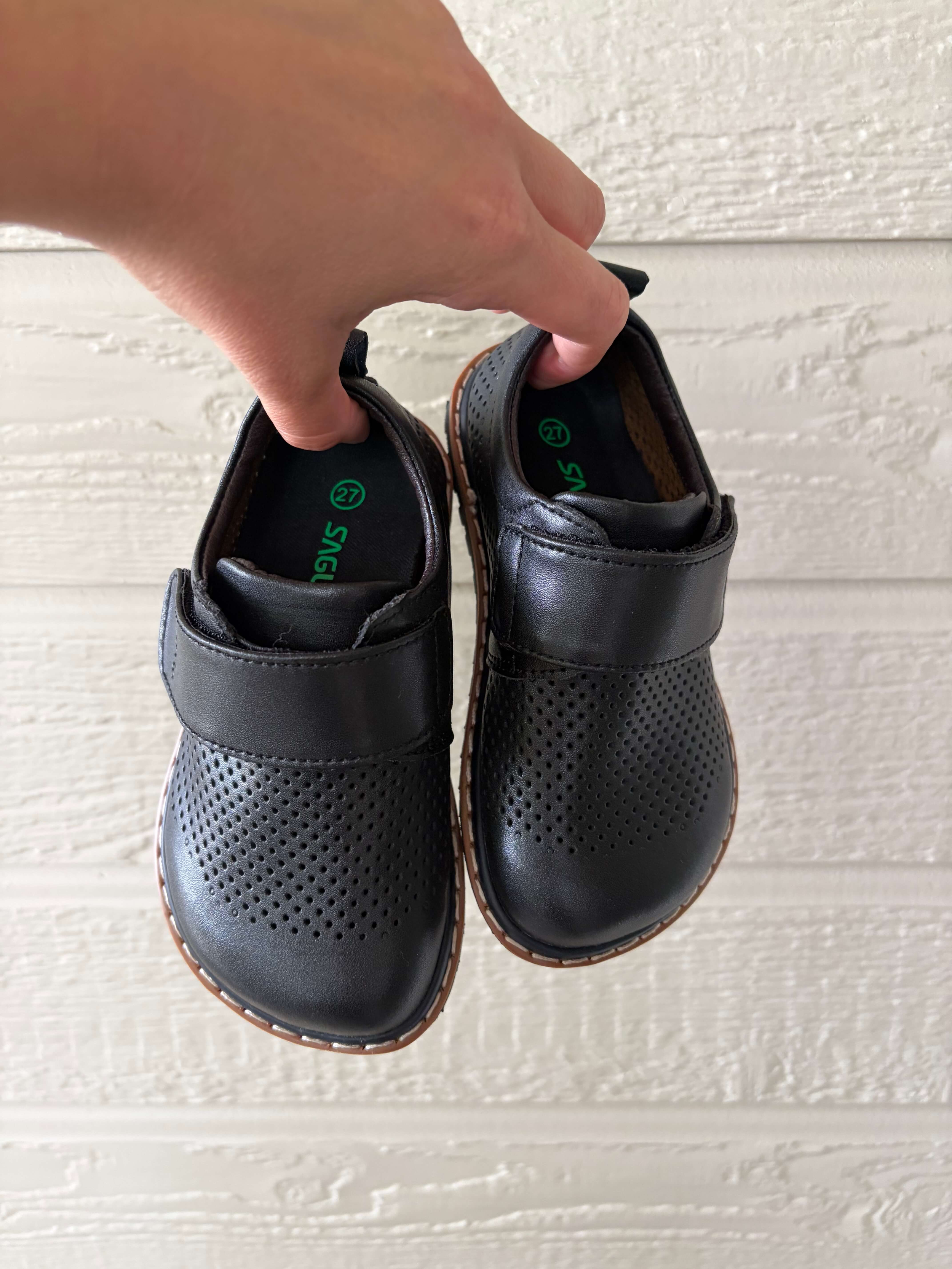 woman holding a pair of the Saguaro Kid's Form I Air Perforated Leather Barefoot Shoes