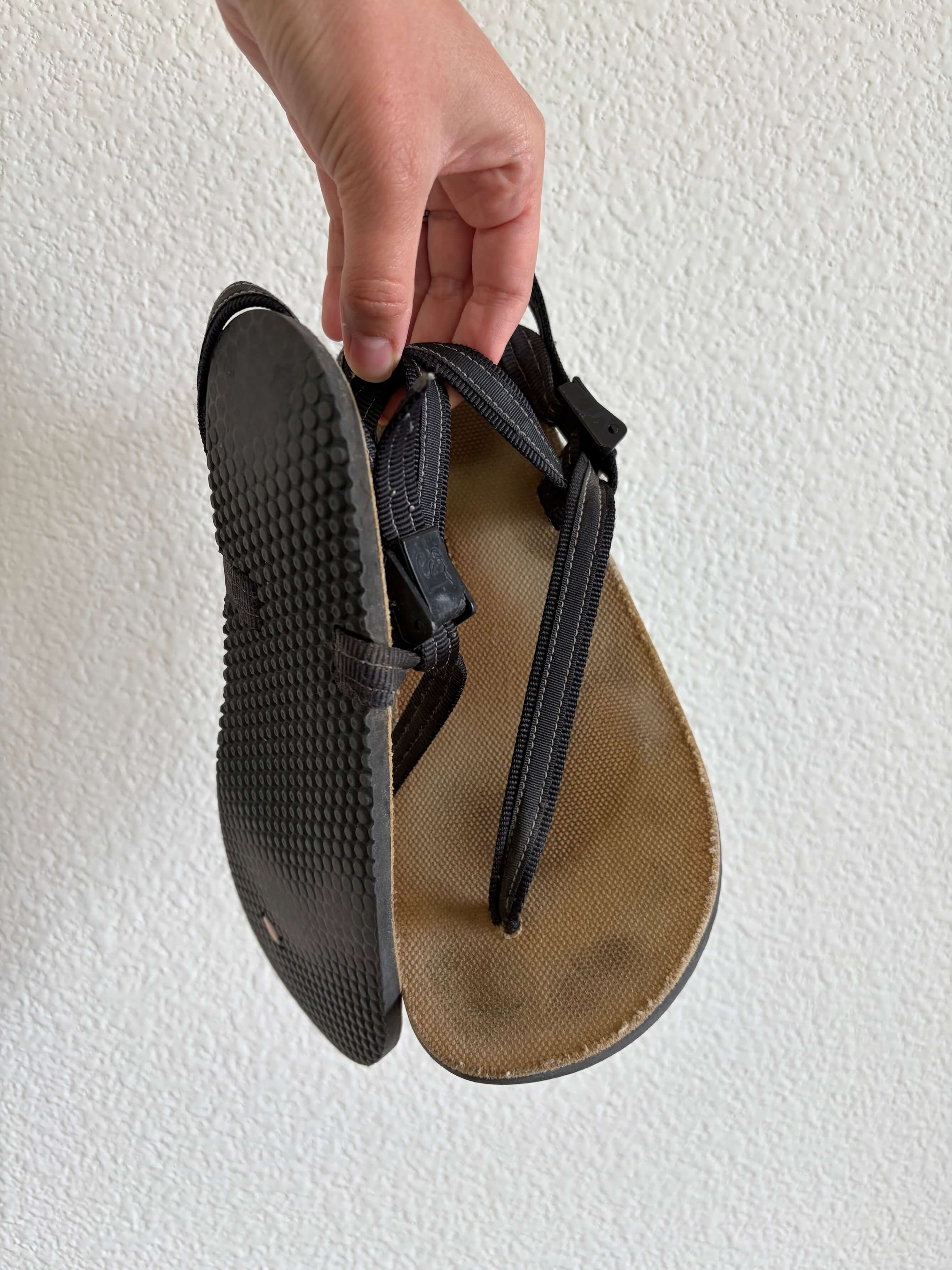 woman holding a pair of earth runners circadian sandals