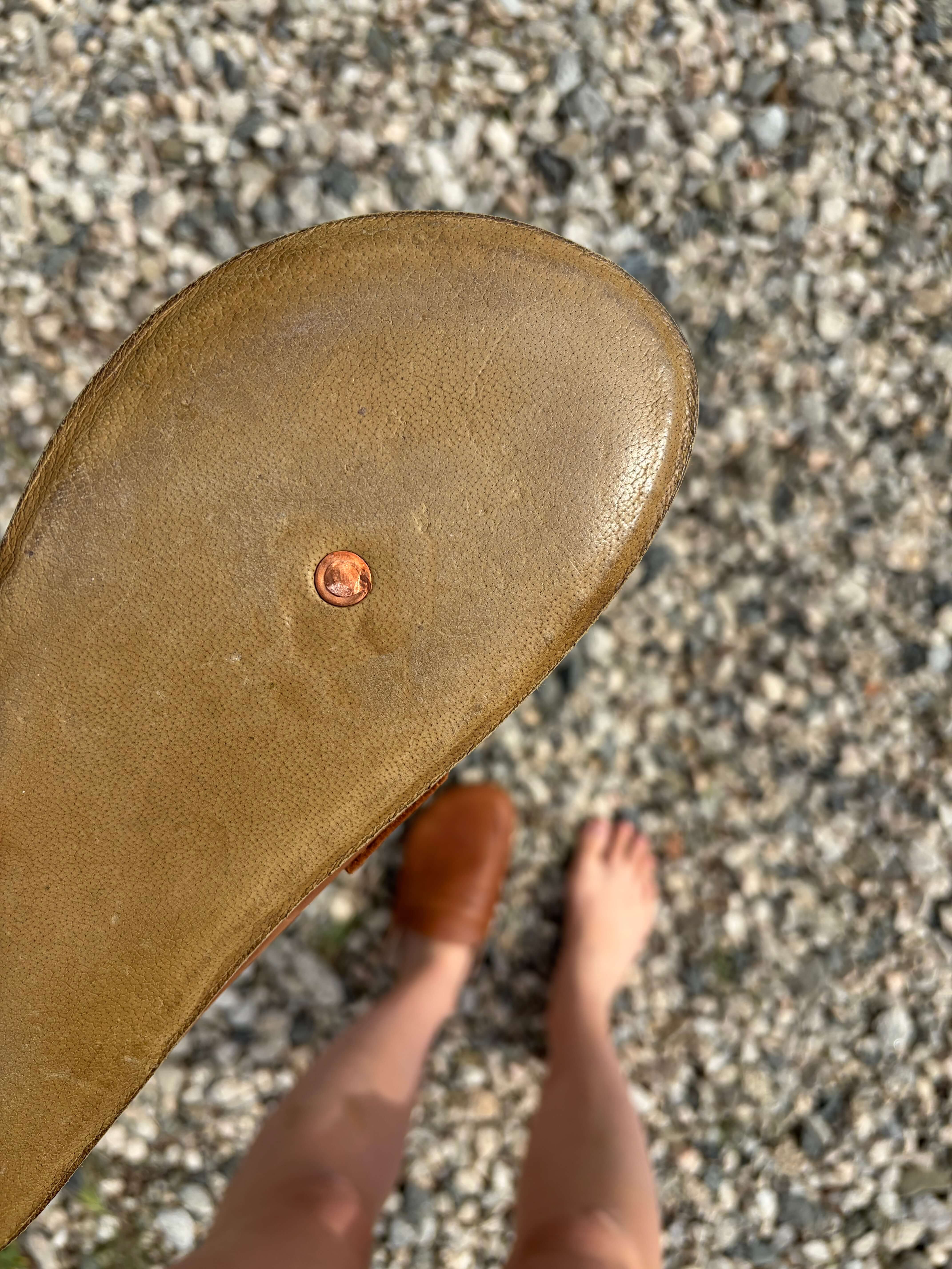 Woman holding a pair of Earthing Harmony Grounding and Earthing Penny Clogs to show the copper rivet in the shoe