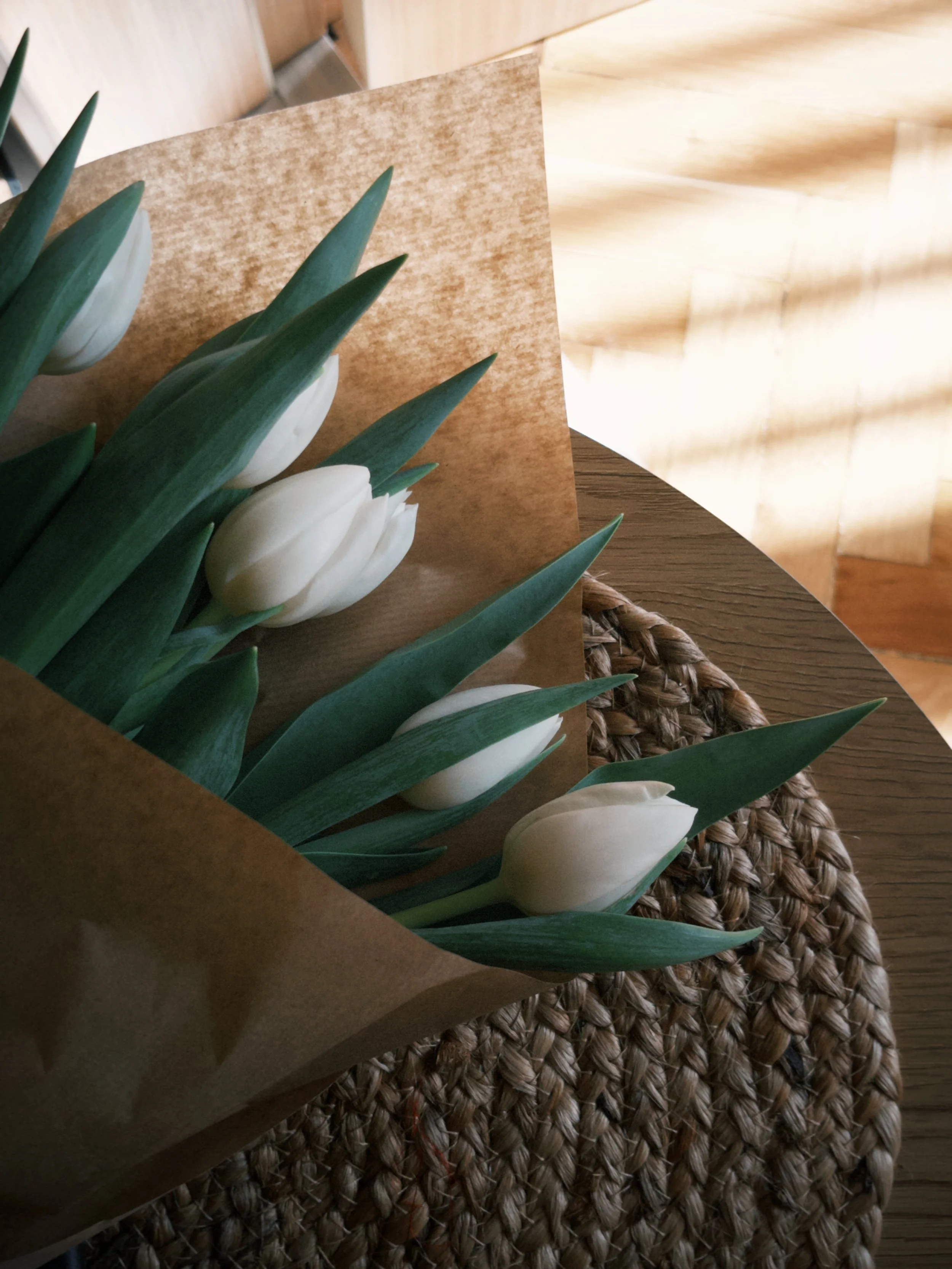 white flowers wrapped in parchment sitting on a round wooden table