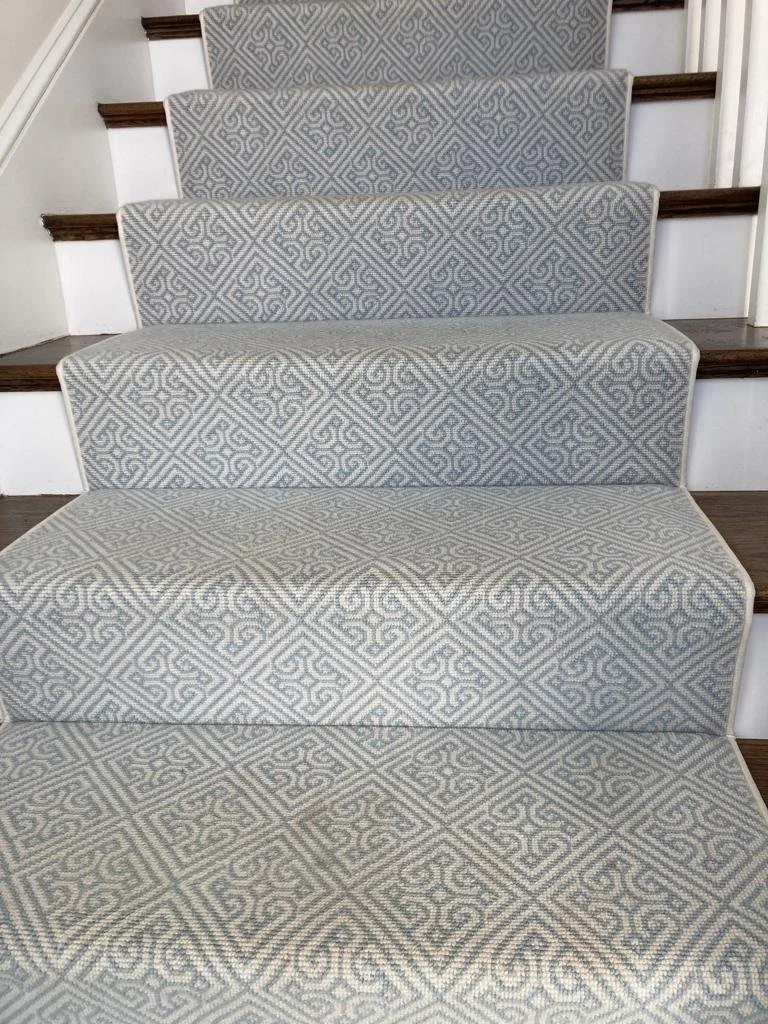A staircase with carpeted steps, featuring a light gray and white geometric pattern.