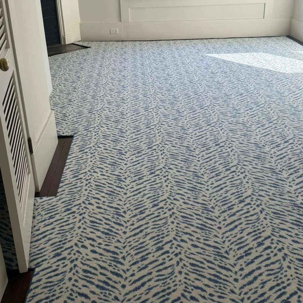 Room with beige walls and a patterned carpet featuring wavy blue and beige lines.