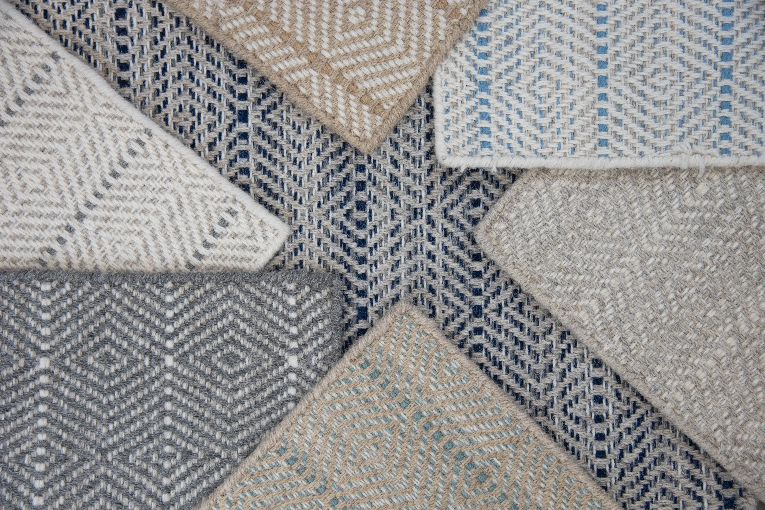 A collection of woven fabric carpets in beige, white, blue, and gray with geometric patterns and textures for carpeting rooms and stairs