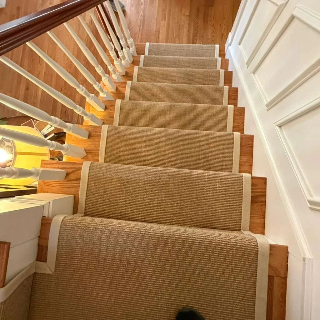 Sisal carpet with wood margin angled down the stairs with wide binding