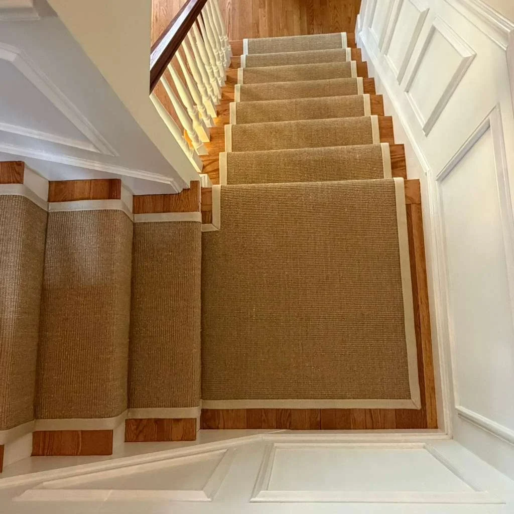 Sisal carpet installed on a stair with a landing . wide binding has miters in the corners.