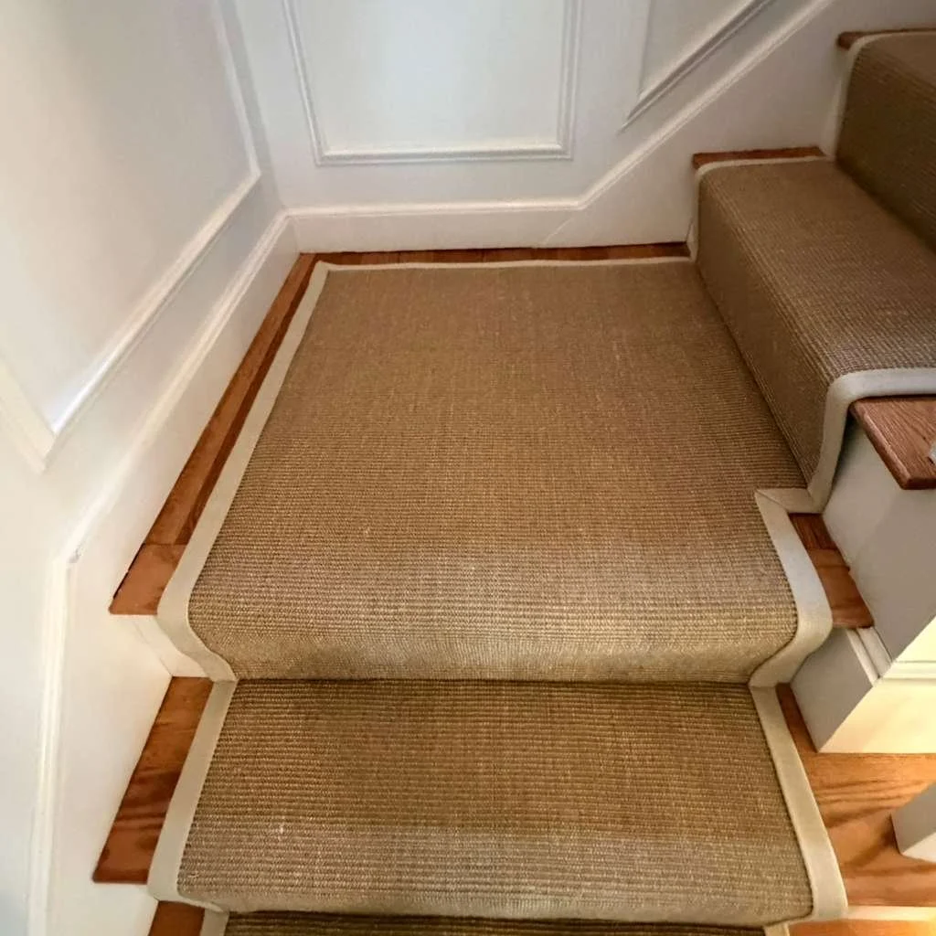 Custom cut sisal carpet and beautiful hand binding on a stair with landing that turns.