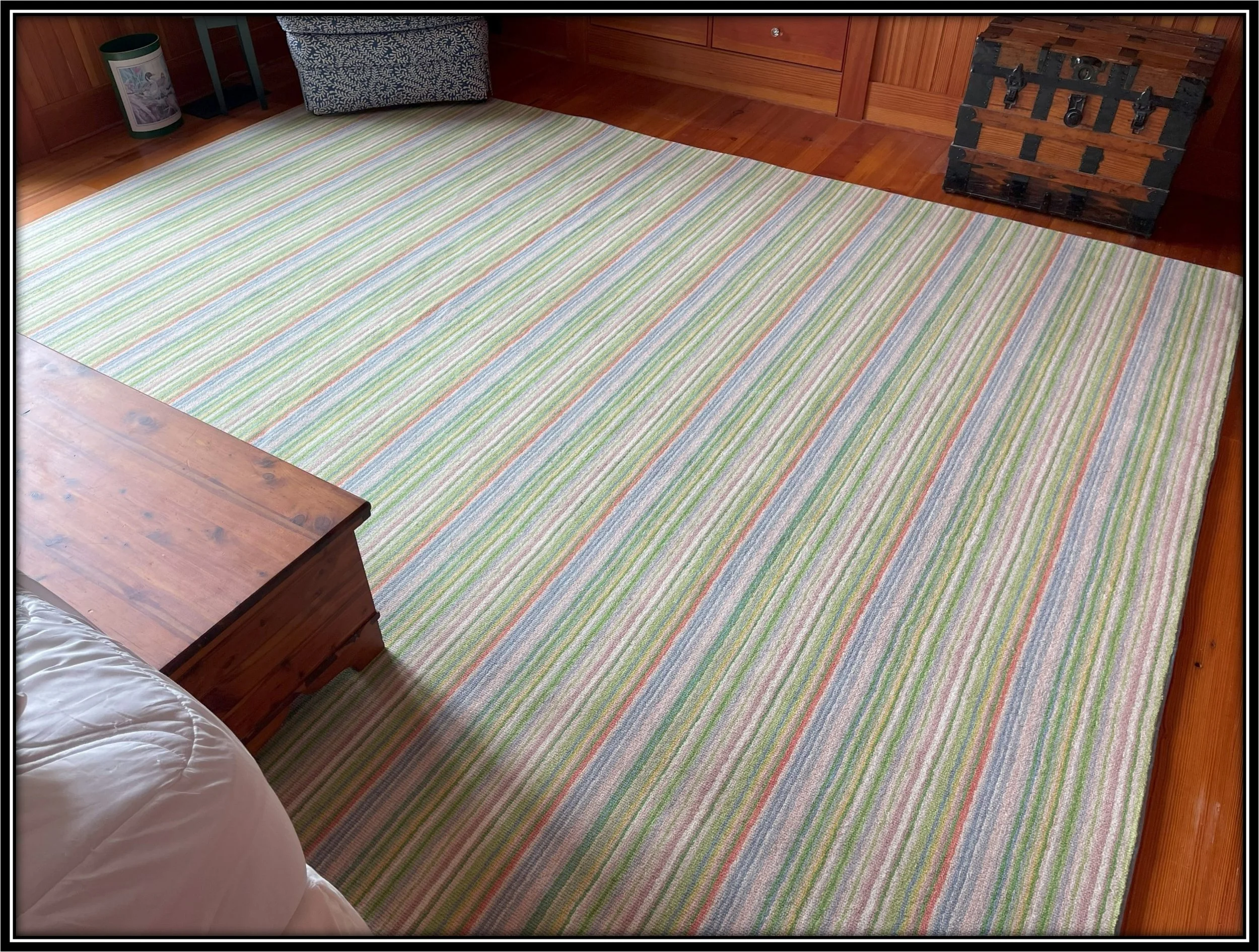 Colorful striped area rug on wooden floor in a cozy bedroom with wooden furniture.