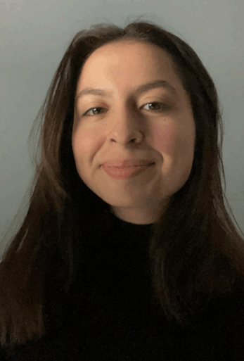 A woman with long dark hair smiling slightly against a plain background.