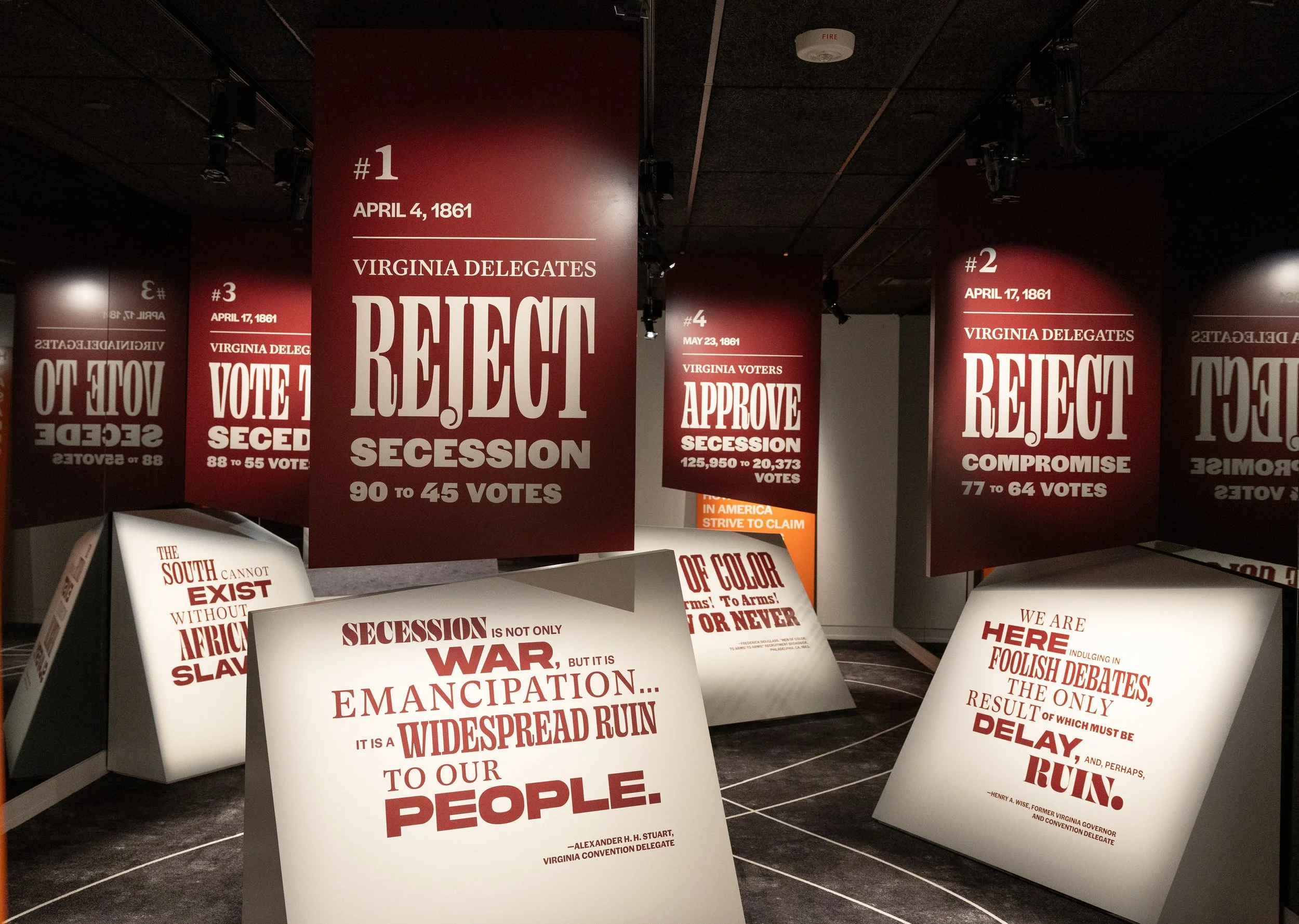 Exhibition with historical flags and text about Virginia's secession votes in 1861, displaying slogans like 'Reject Secession,' 'Approve Secession,' and quotes about war and emancipation.